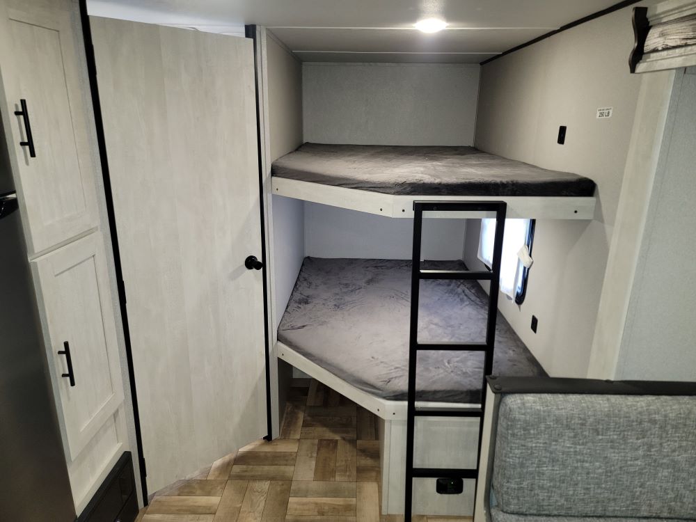 Inside an RV rental: comfortable bunk beds with a ladder and window, perfect for family adventures on the road.. Forest River Shasta 2022