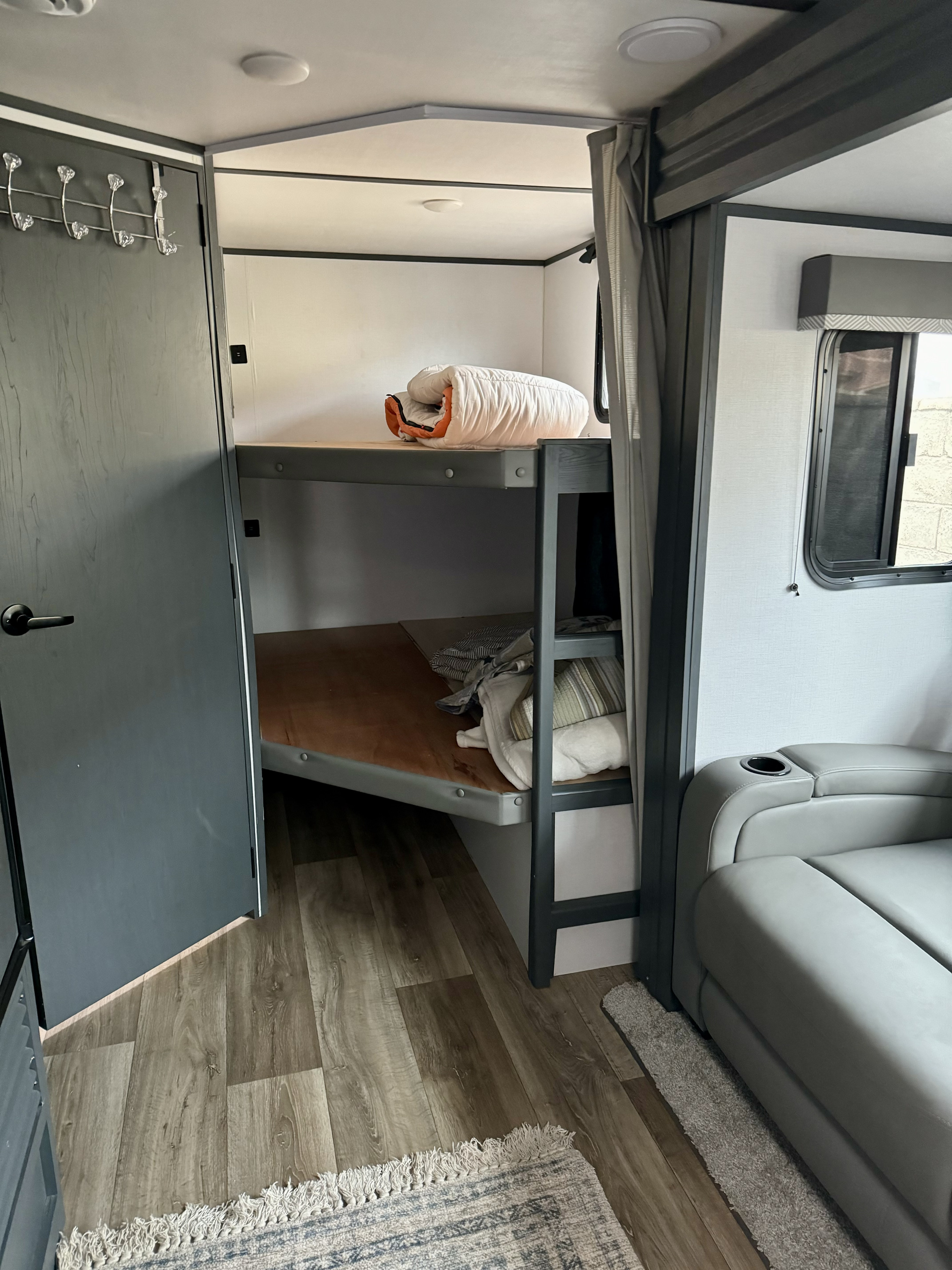 RV rental: A cozy sleeping and living area with bunk beds, a sofa with a cup holder, and wood-look flooring.. Keystone RV Bullet Crossfire 2022
