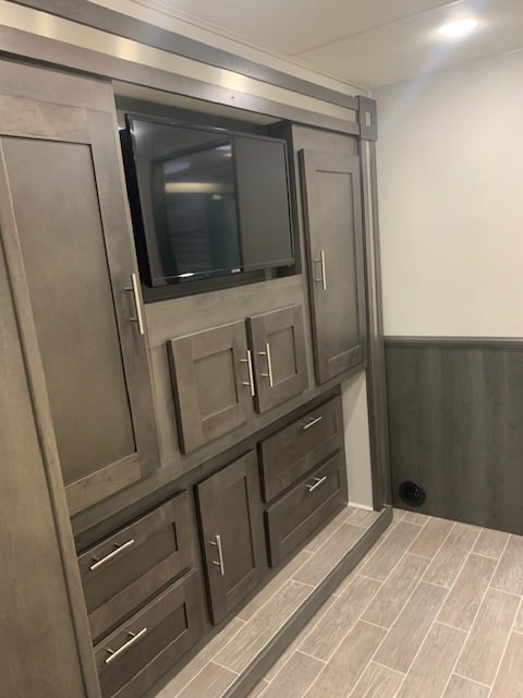 RV rental interior: A built-in entertainment center with a TV, dark wood-look cabinets, and drawers for ample storage.. Georgetown GT5 2023