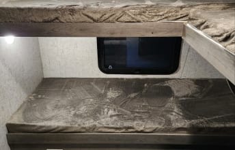 RV rental bunk beds: an upper and lower bunk with textured mattresses, a window, and light. Great for camping trips.. Coachmen Apex 2019