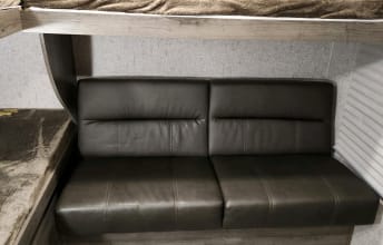 RV rental interior: Dark faux leather sofa with two cushions under a wood bunk bed, optimizing compact space.. Coachmen Apex 2019