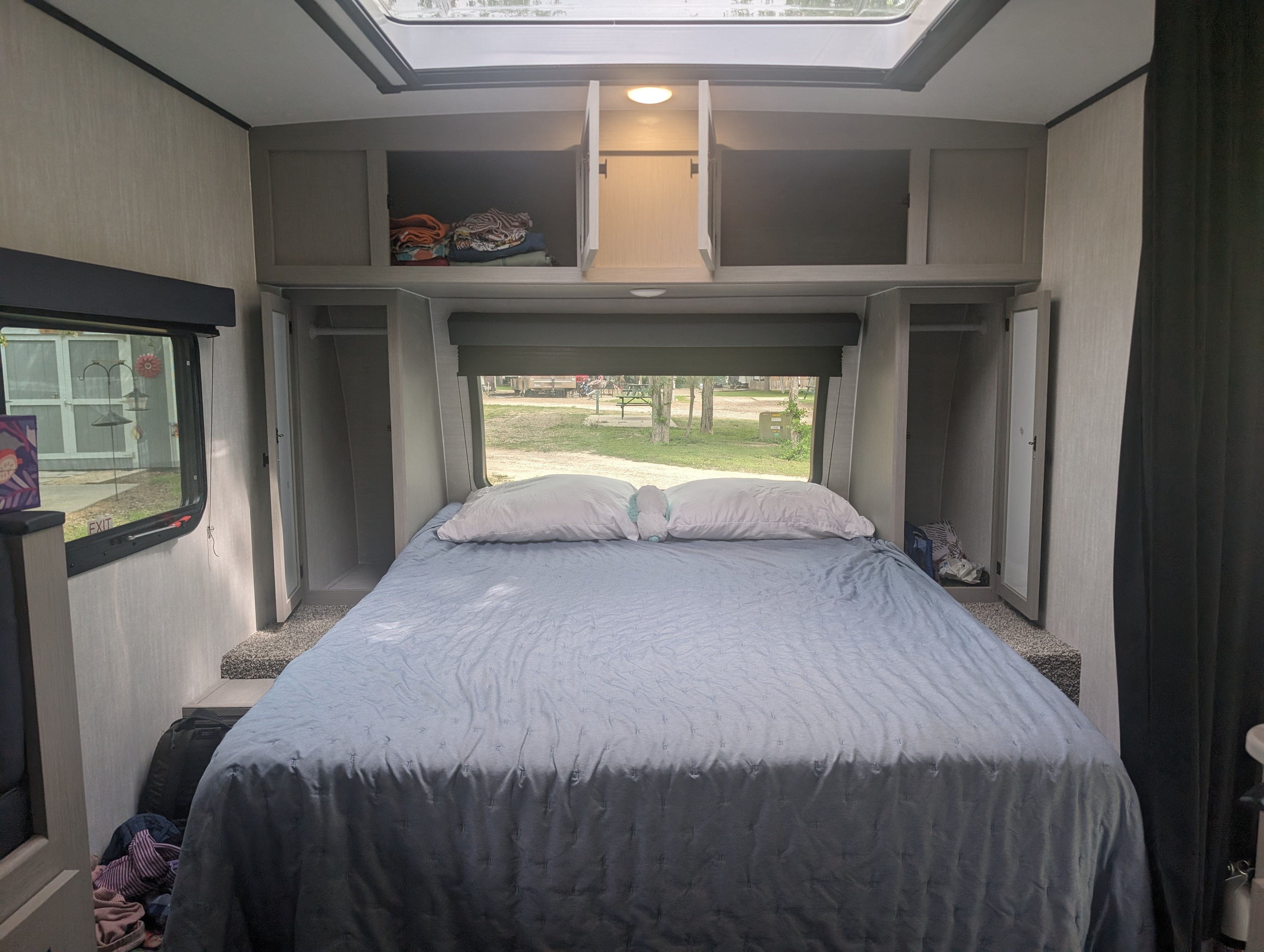 Spacious RV rental bedroom featuring a large bed, ample overhead cabinets & wardrobes, and a scenic window view.. Forest River Coachman Apex Nano 208BHS 2024