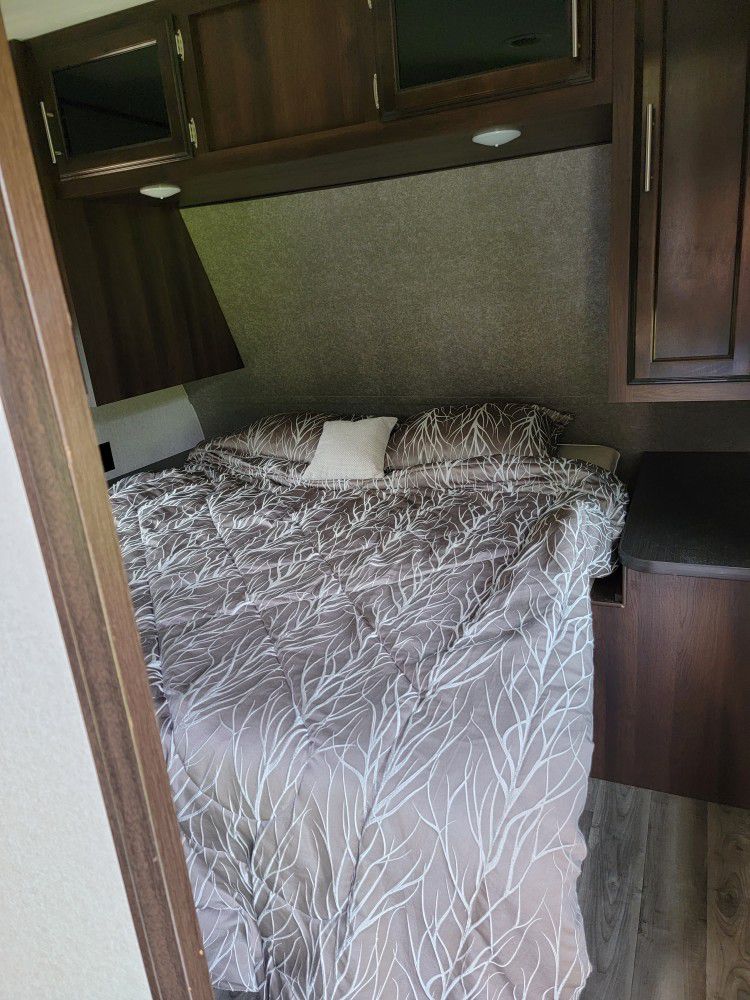 Cozy RV rental bedroom with a comfortable bed and patterned comforter, featuring overhead storage cabinets.. Jayco Jay Flight 2019