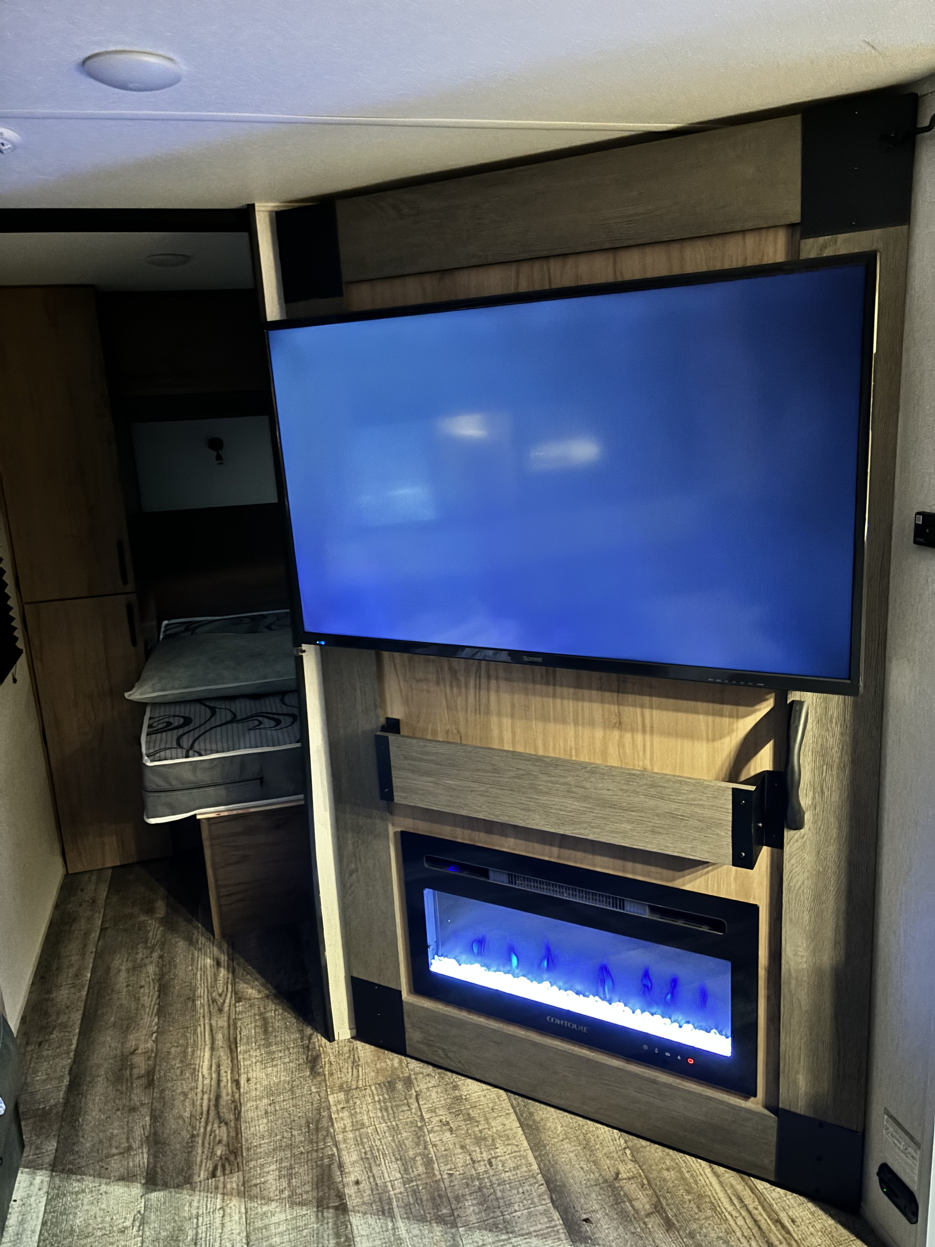 This RV rental interior features a TV mounted above an electric fireplace, providing a modern and comfortable living space.. Forest River Campsite Reserve 2024