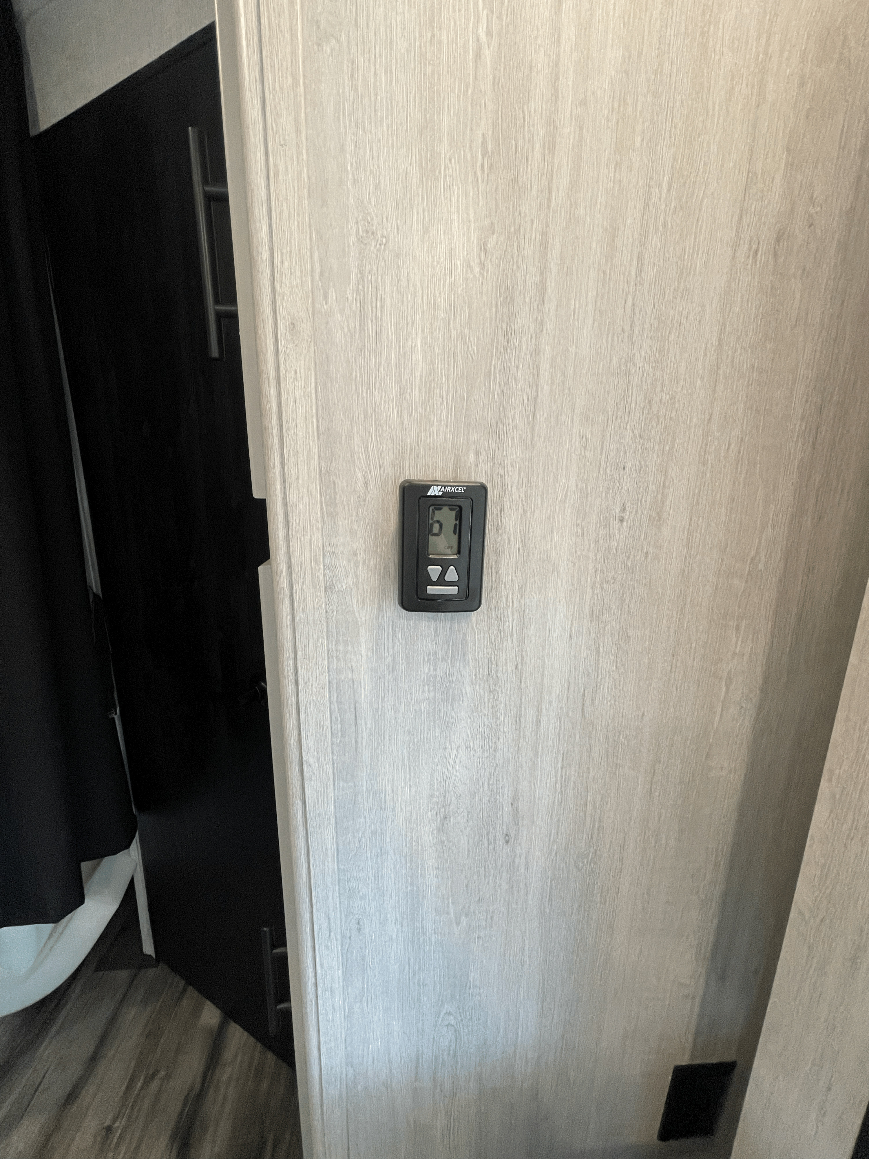 RV rental: Digital thermostat showing 67°F (off) on a light wood wall, beside a dark door with a metal handle.. Crossroads RV Sunset Trail 242BH 2024