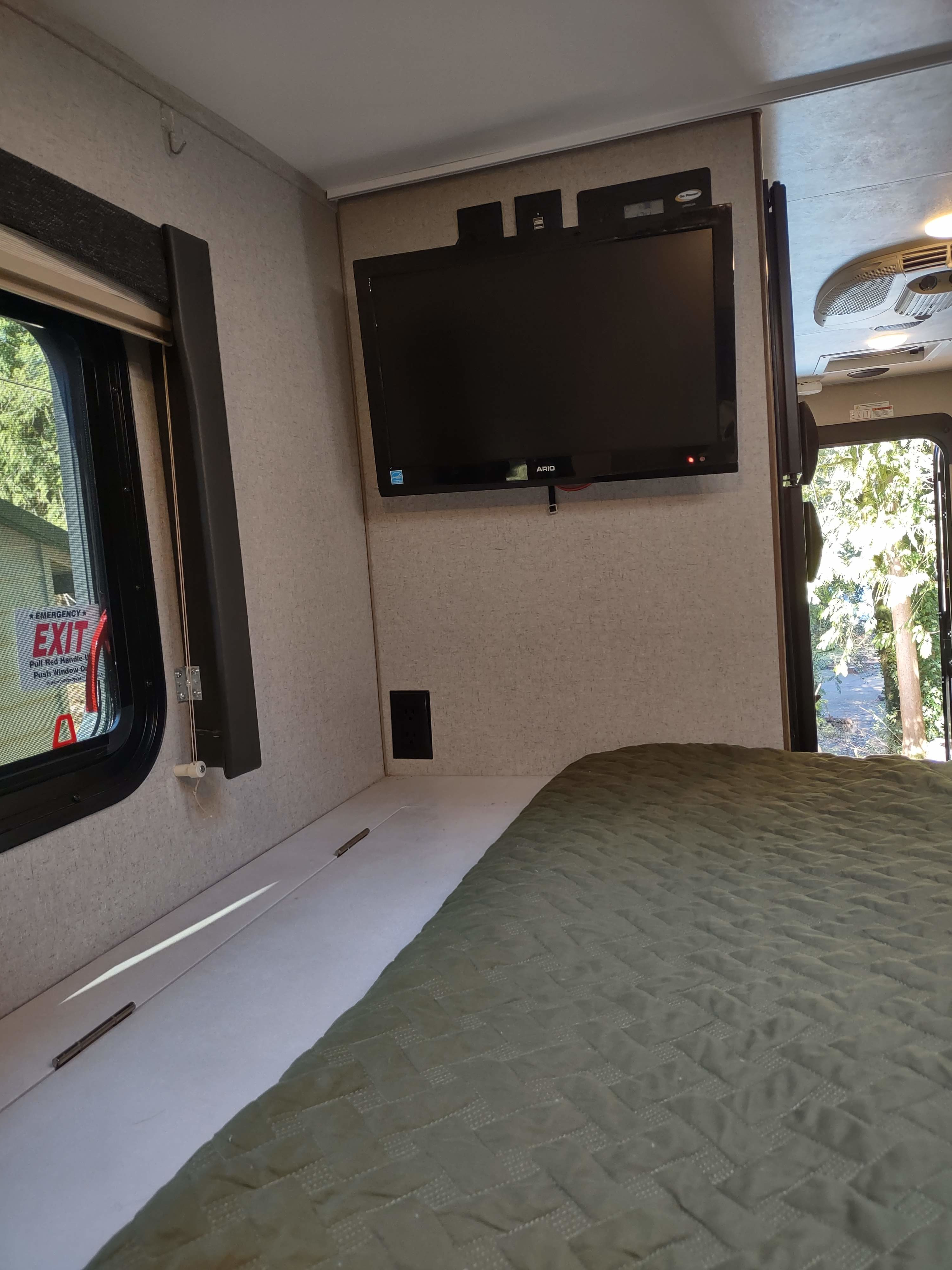 Cozy RV rental bedroom with a mounted TV, comfortable bed, emergency exit window, and a view to the outdoors.. Adventurer Adventurer 2021
