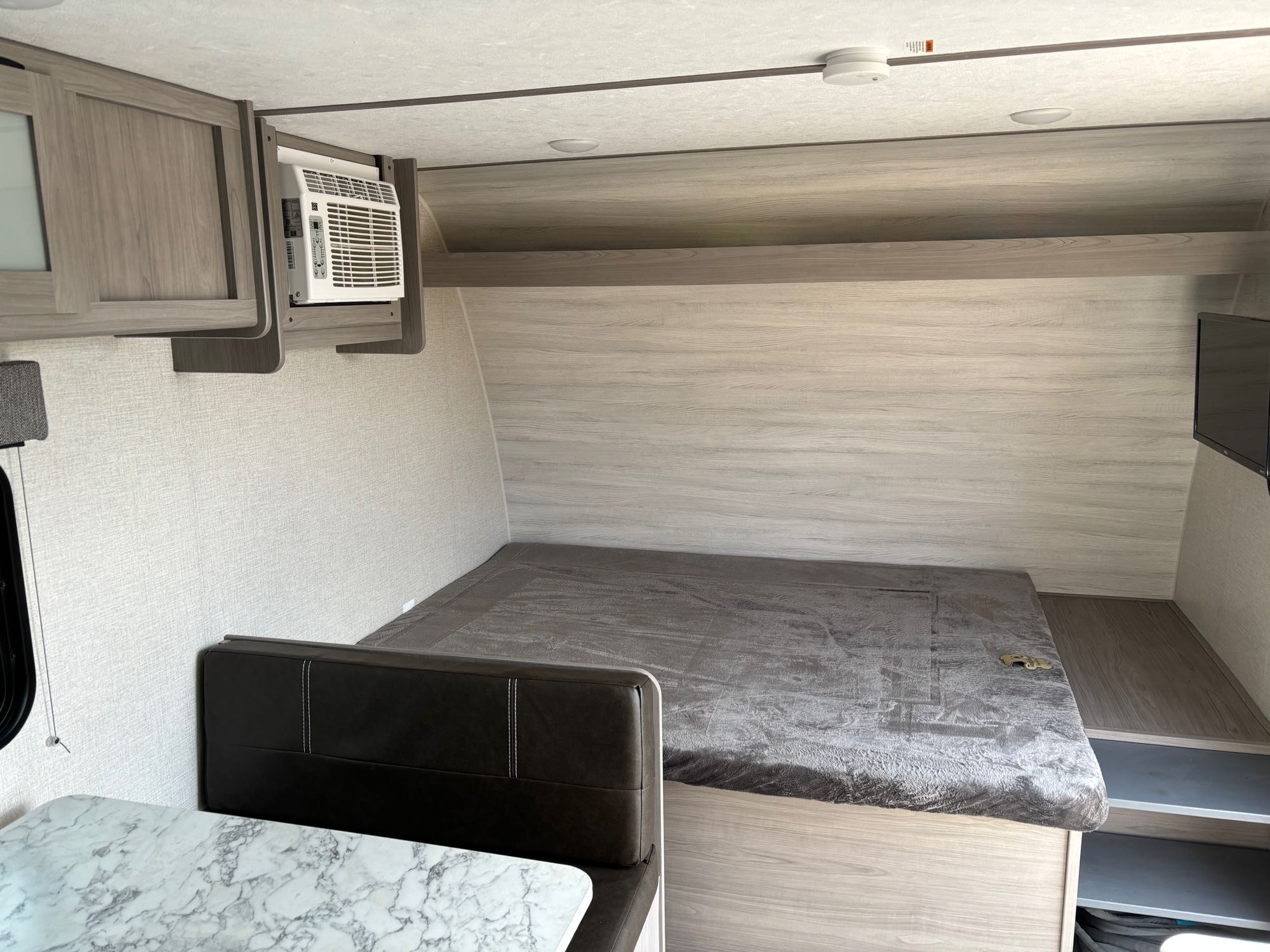Cozy RV rental interior with a comfy bed, compact dinette, AC, and overhead storage. Ideal for your next camper journey.. Dutchmen Coleman Lantern LT 2023
