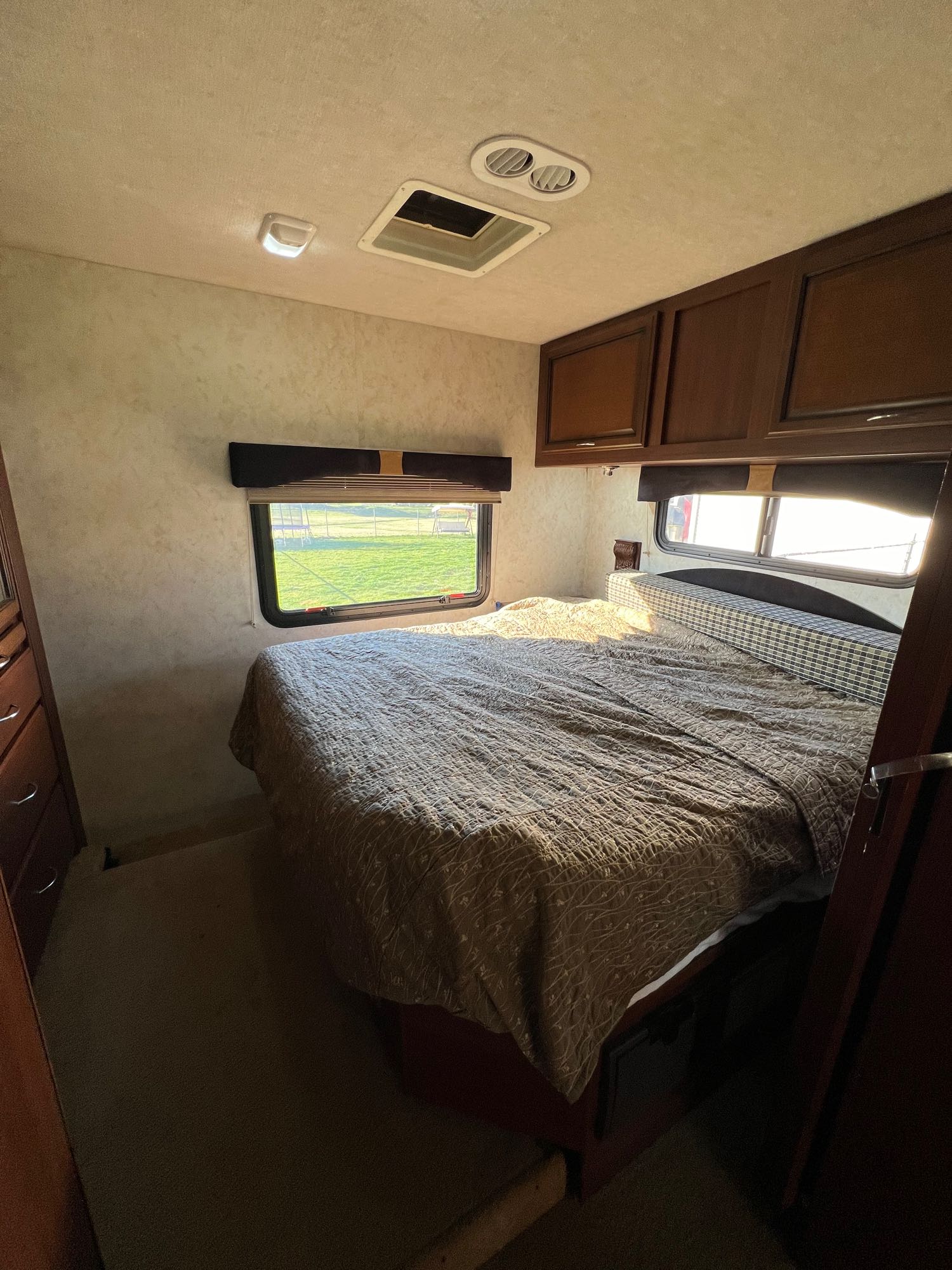 Comfortable bedroom in an RV rental, featuring a bed, windows with a view, and overhead storage for a cozy stay.. Storm Storm Motorhome 2011