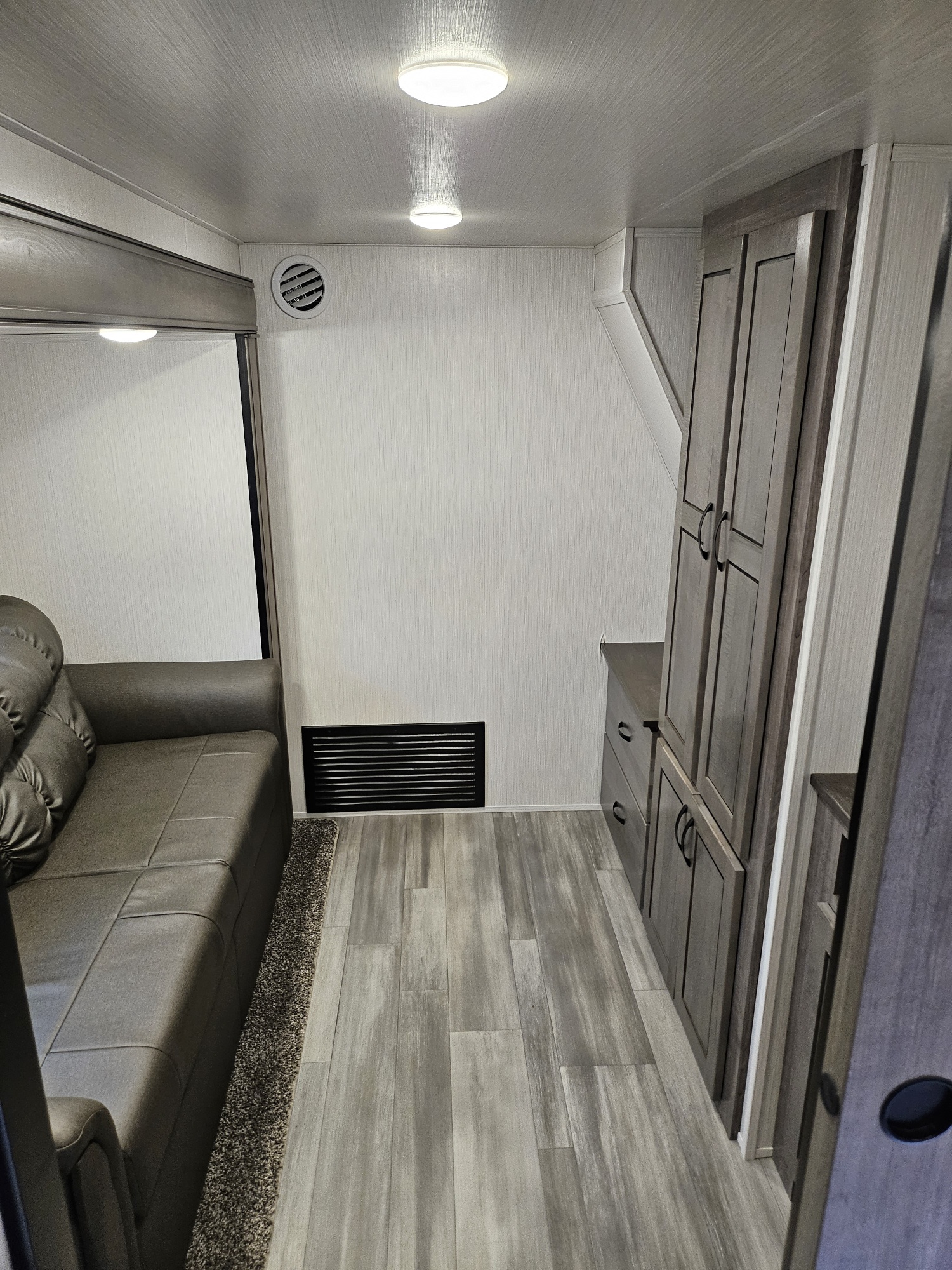 Inside an rv rental: a cozy living space with a grey sofa, light wood flooring, and sleek storage cabinets.. Forest River Cedar Creek Fifth Wheel 2022