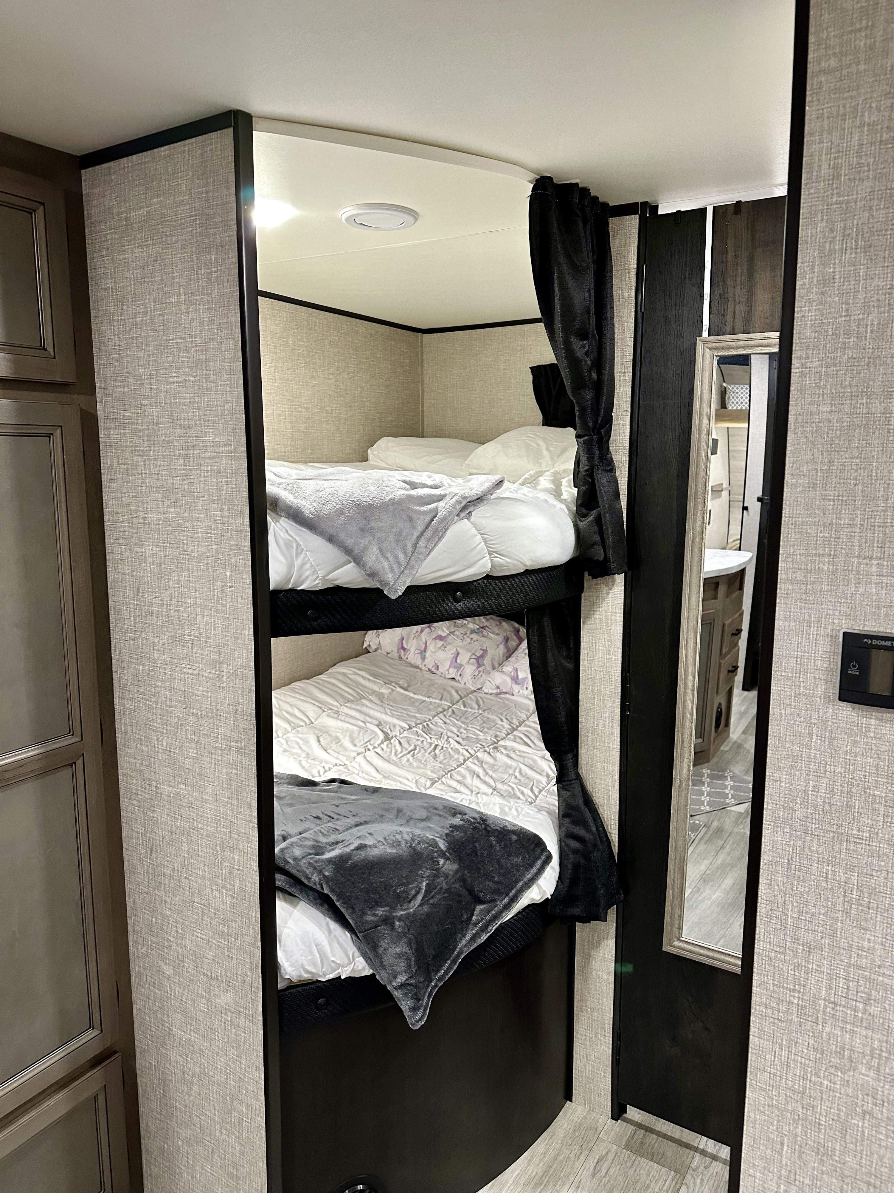 Modern RV rental interior featuring cozy stacked bunk beds with white bedding and privacy curtains.. Jayco Jay Flight SLX 2022