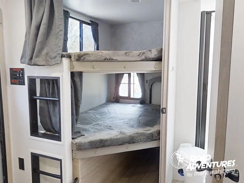 RV rental interior features cozy bunk beds, windows with curtains, and a control panel, ideal for family trips.. Winnebago Minnie 2801BHS 2024