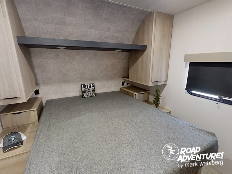 Interior of an RV rental bedroom showing a gray bed, light wood cabinets, and window. Ideal for camping adventures.. Winnebago Minnie 2801BHS 2024
