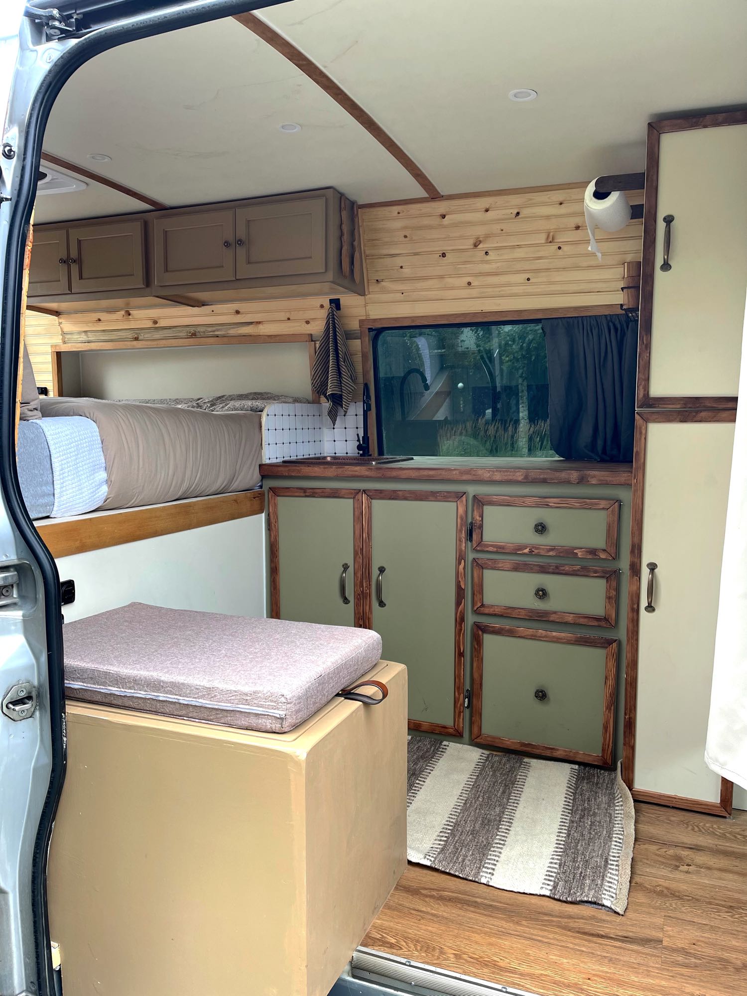 Cozy RV rental interior with bed, wood cabinets, kitchenette, and storage. Perfect for mobile comfort and adventure.. Mercedes Sprinter 2019