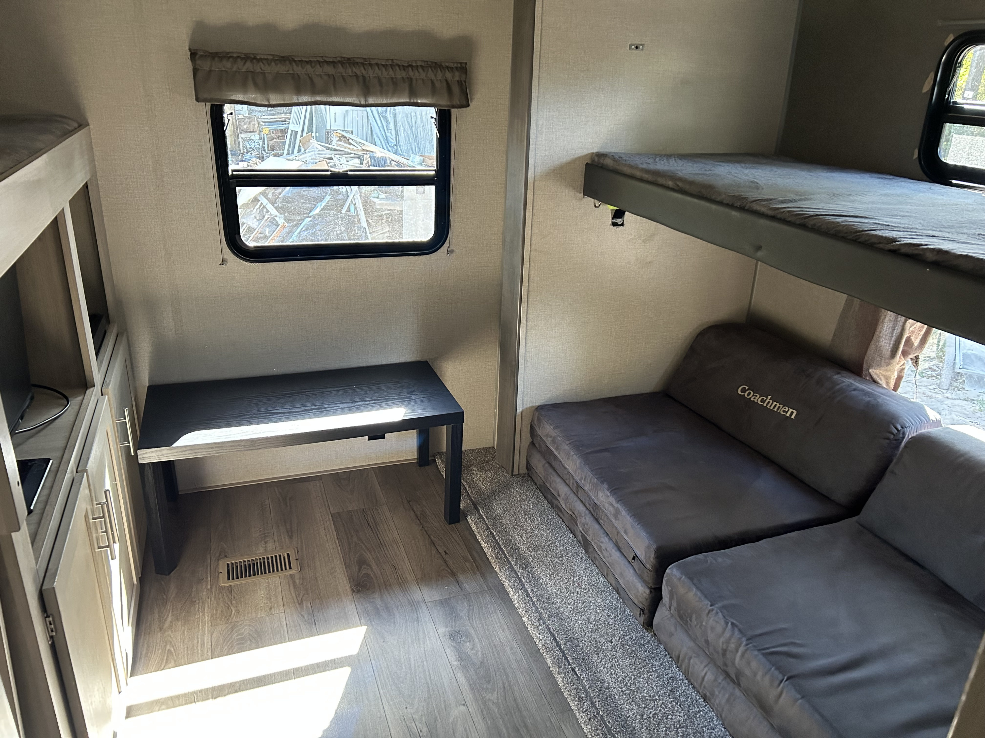 Modern rv rental interior: bunk beds, flexible sofa seating, and a desk. A comfortable space for your travels.. Coachmen Catalina Legacy 2022