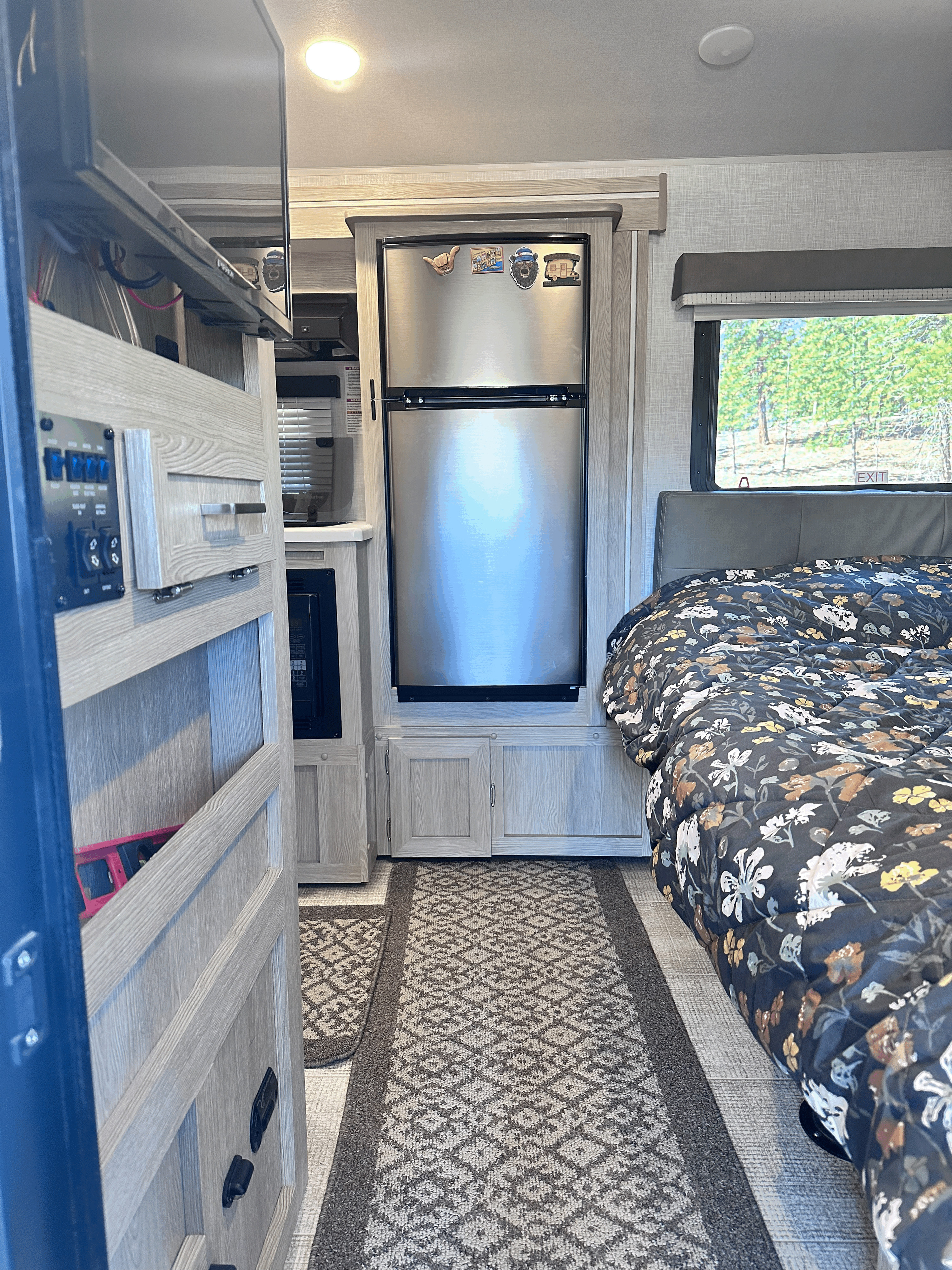 RV rental interior: View of the bed, stainless steel fridge, microwave, and TV in a light wood setting.. Forest River Rockwood Geo Pro 2021