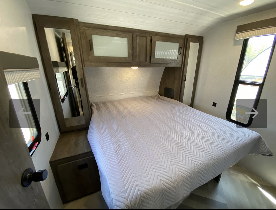 Cozy RV rental bedroom featuring a comfy bed, overhead cabinets, mirrored wardrobe, and windows for light.. Forest River Salem 2022