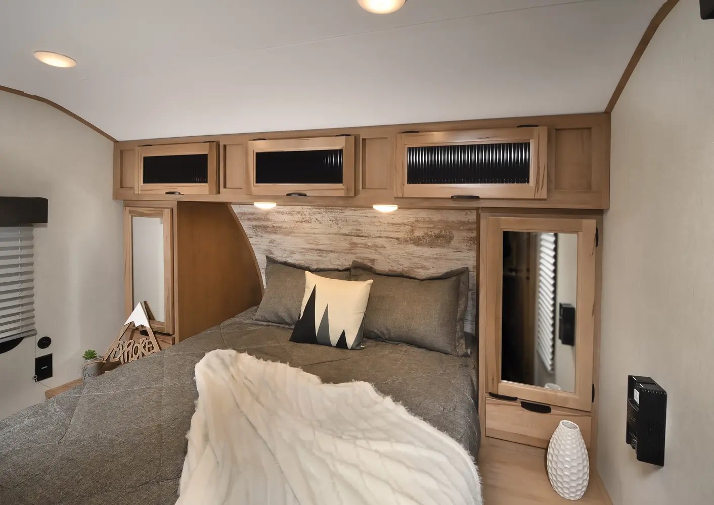 Cozy RV rental bedroom showcasing a modern interior with a comfy bed, rustic headboard, and overhead storage for travel comfort.. Forest River Cherokee Alpha Wolf 2024
