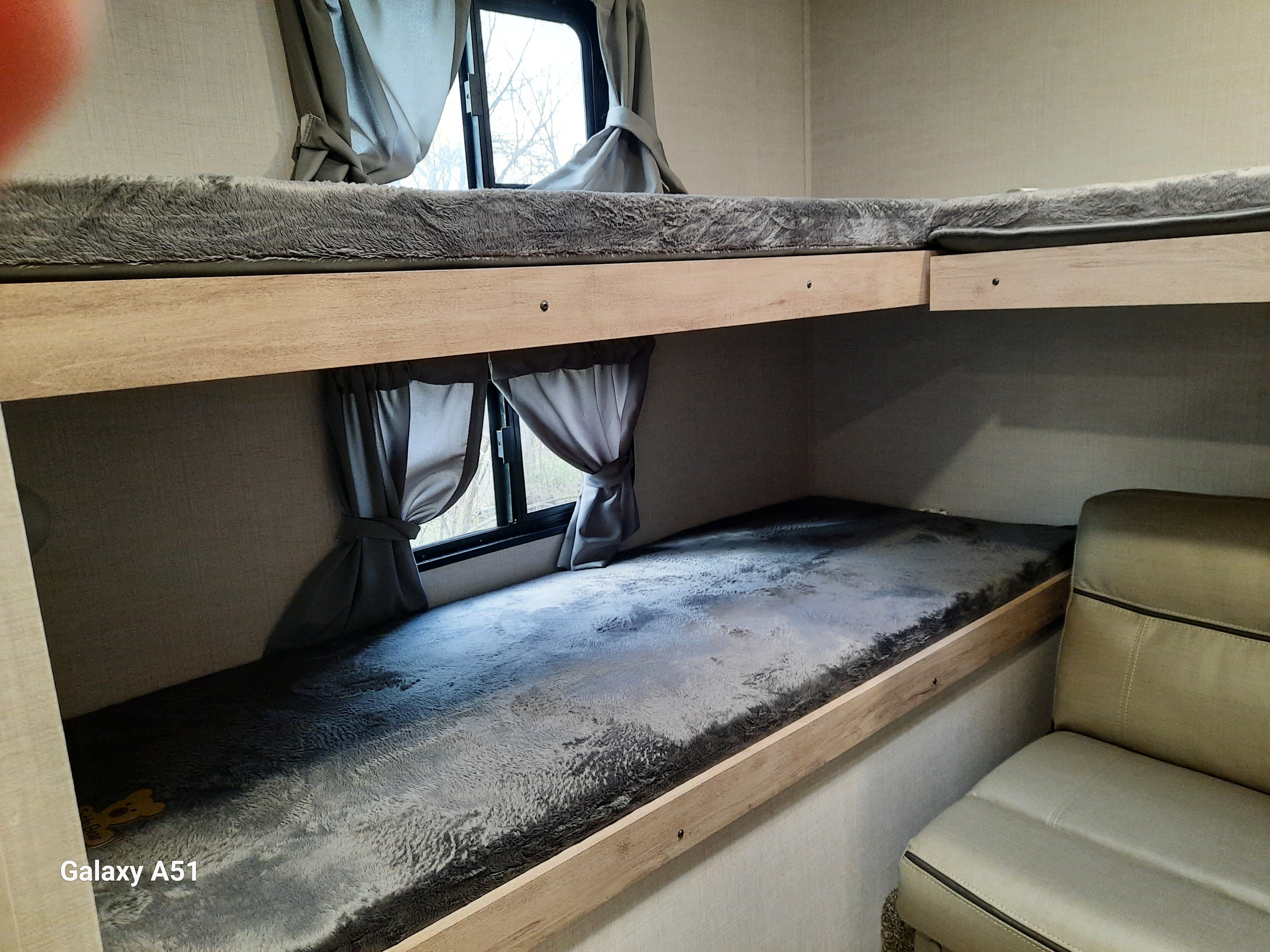 Inside an RV rental: Compact bunk beds with plush grey bedding and windows, ideal for campers.. Gulf stream Kingsport 2024