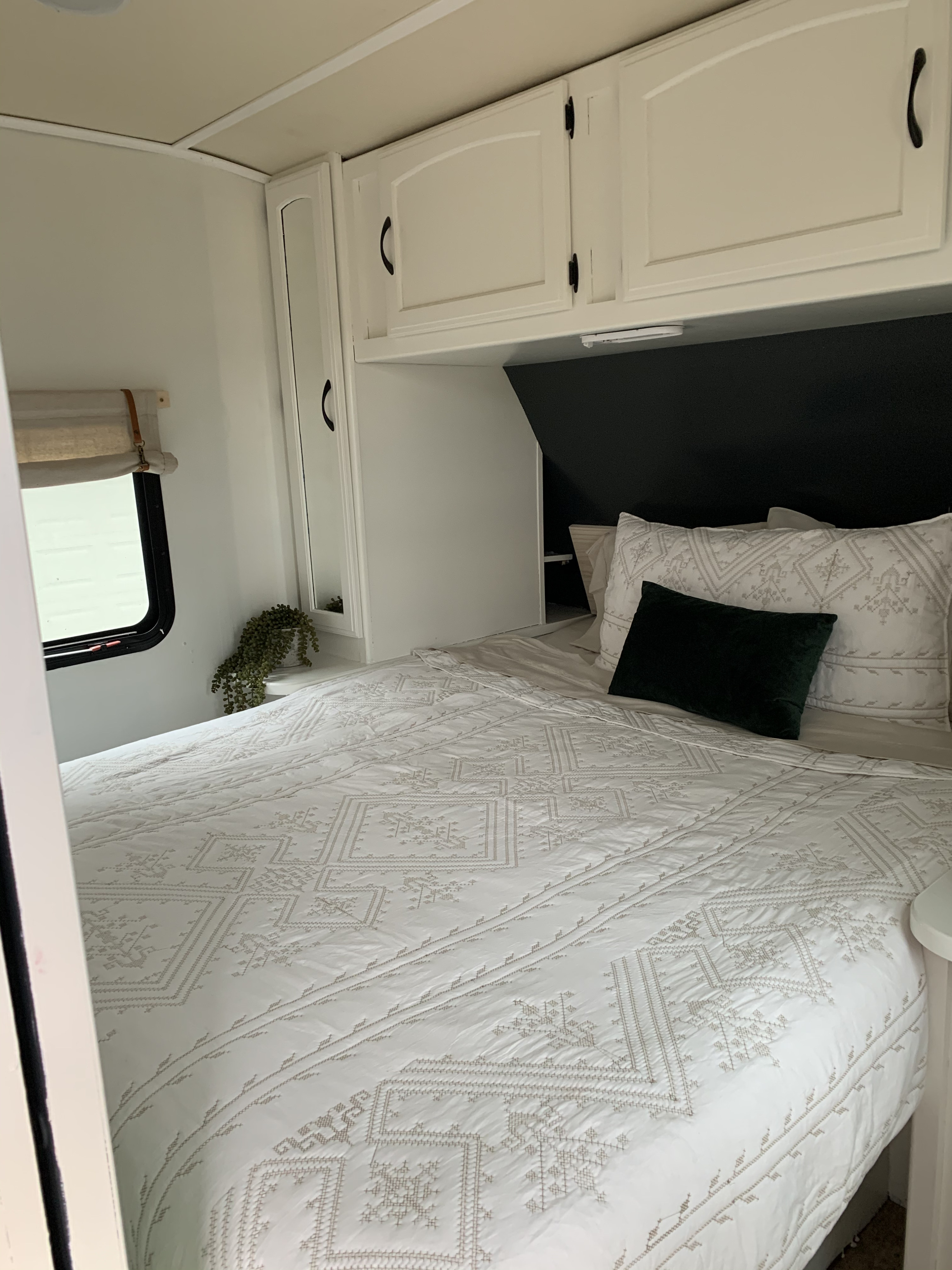 Cozy RV rental bedroom with white patterned bedding, overhead cabinets, and a compact design.. Jayco White Hawk 2016