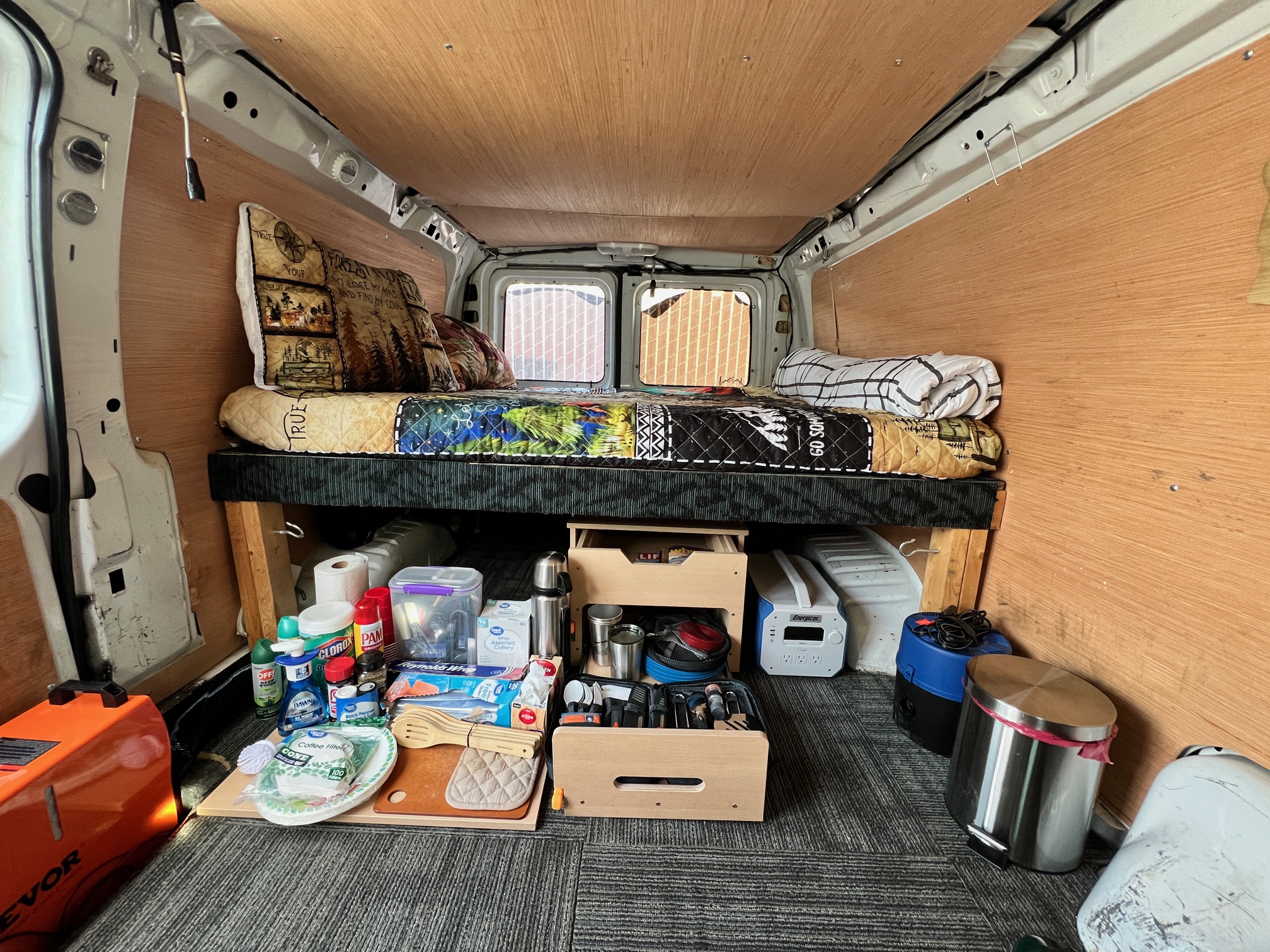 Cozy rv rental camper van interior: bed, organized kitchen supplies under it, and portable power. Ideal for road trips and camping.. Ford Econoline 150 1997