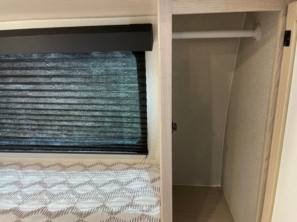 Cozy RV rental bedroom featuring a window with blind, bed, and built-in closet for compact travel storage.. Coachmen Apex Nano AAPT186BH 2024