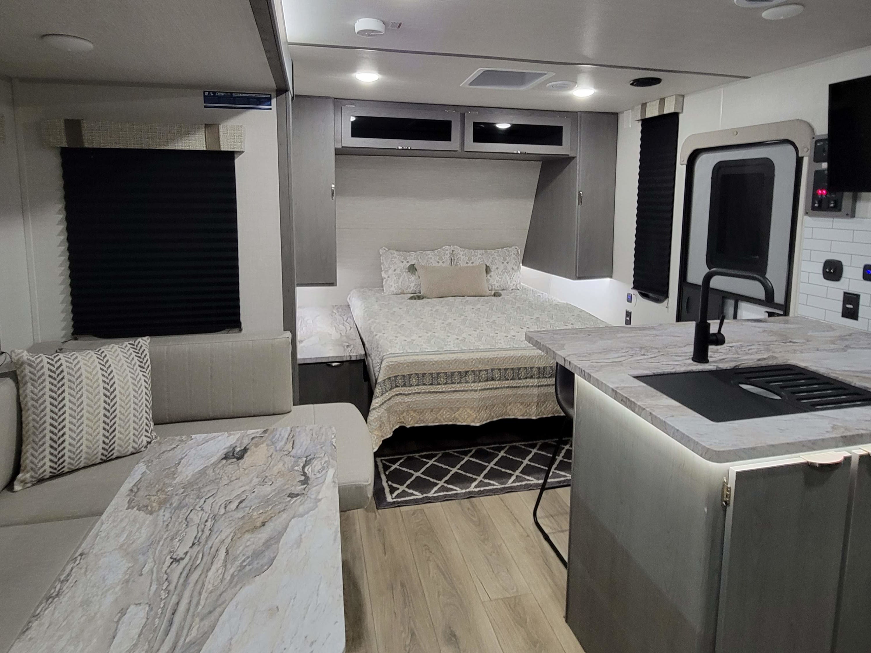 Modern rv rental interior: full view of a stylish bedroom, living space with sofa, and kitchenette with sleek finishes.. Forest River ozark 2440bhkx 2024