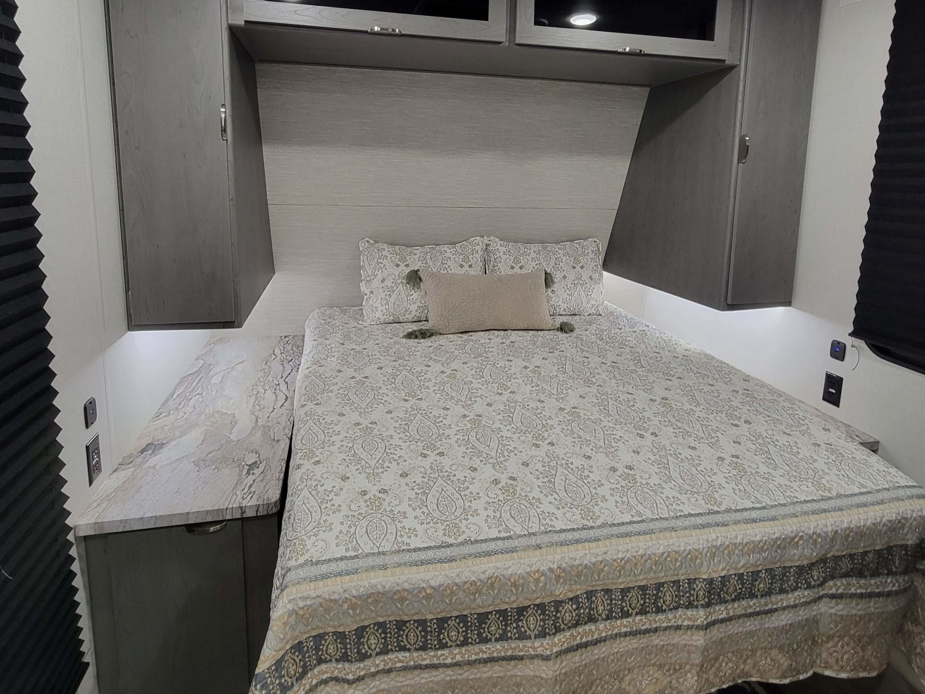 Spacious RV rental bedroom with a comfortable queen bed, modern cabinetry, marble-look counters, and ambient lighting.. Forest River ozark 2440bhkx 2024
