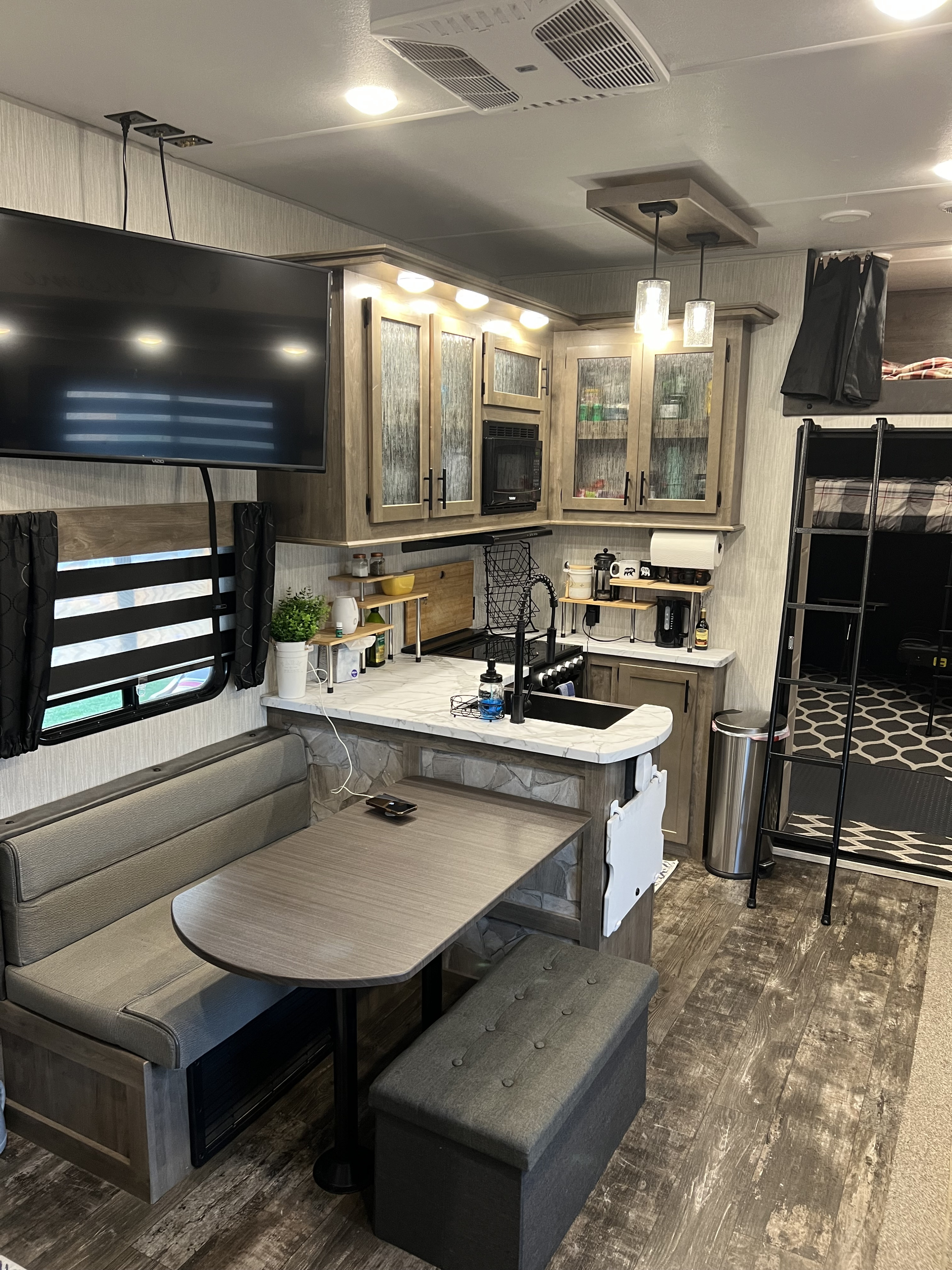 Cozy RV rental interior featuring a compact kitchen, dining area, wall-mounted TV, and bunk beds.. Forest River Cherokee Wolf Pack Toy Hauler 2021