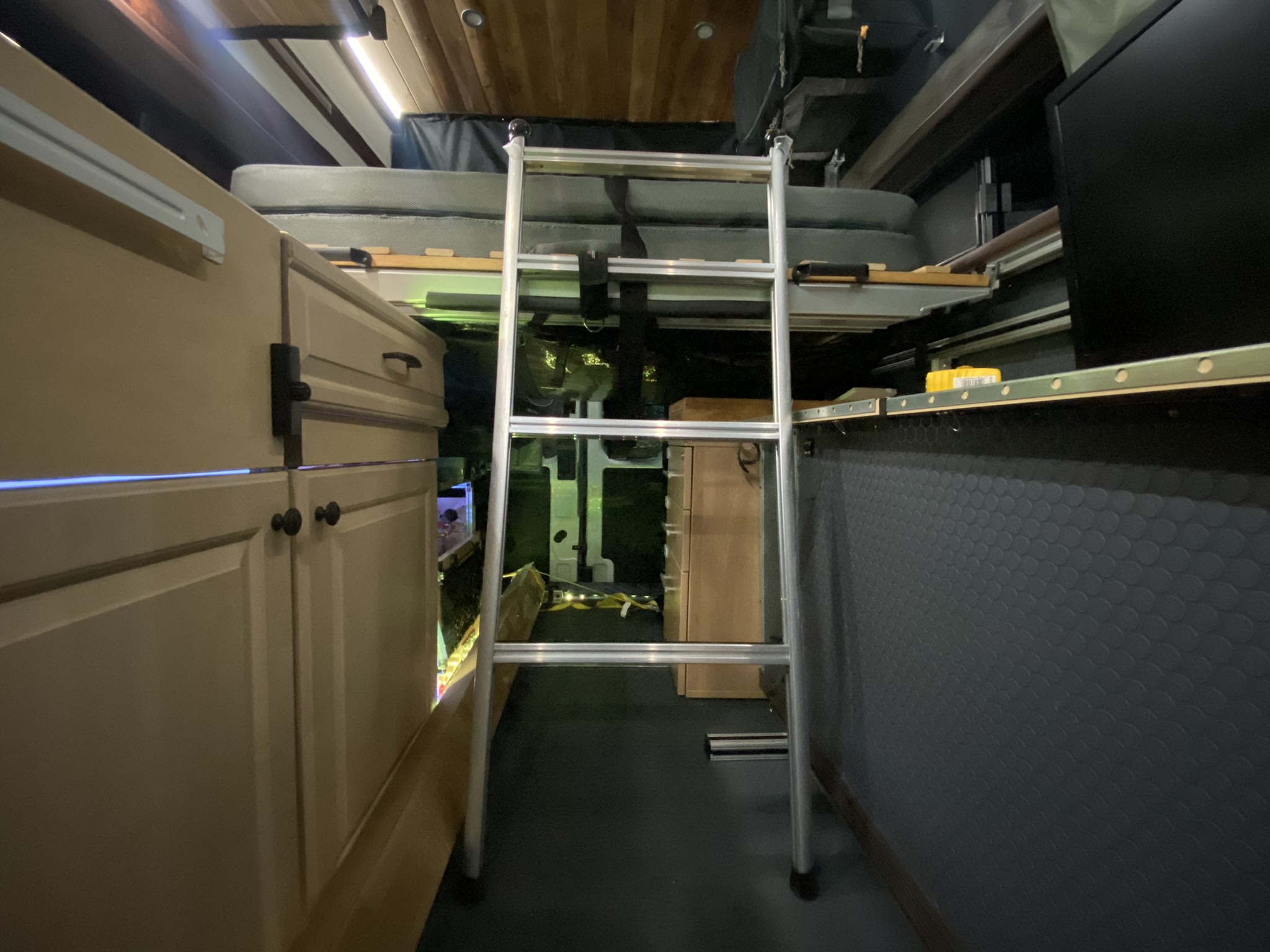 Step into this cozy RV rental's camper van interior, featuring a ladder to a comfortable raised bunk bed and built-in storage.. Ford Transit Transit 2022