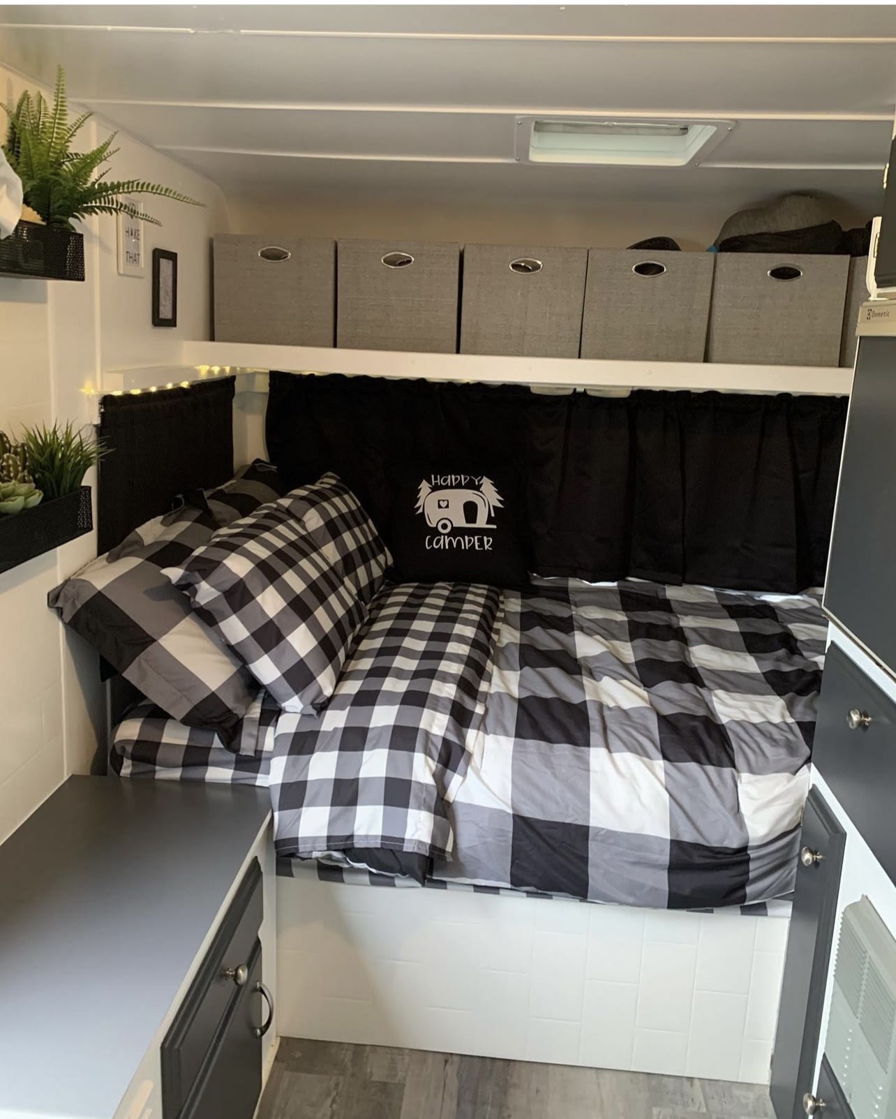 Inside a stylish RV rental! Features a comfy bed with black/white plaid, overhead storage, and fun decor.. Bonair Bonair 1989