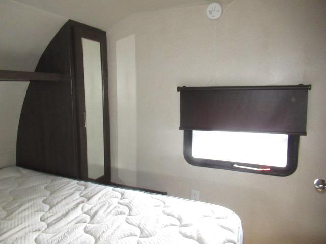 Cozy RV rental bedroom: features a comfortable bed, mirrored wardrobe, and a window with a pulled-down shade.. Wildwood 31KQBTS 2018