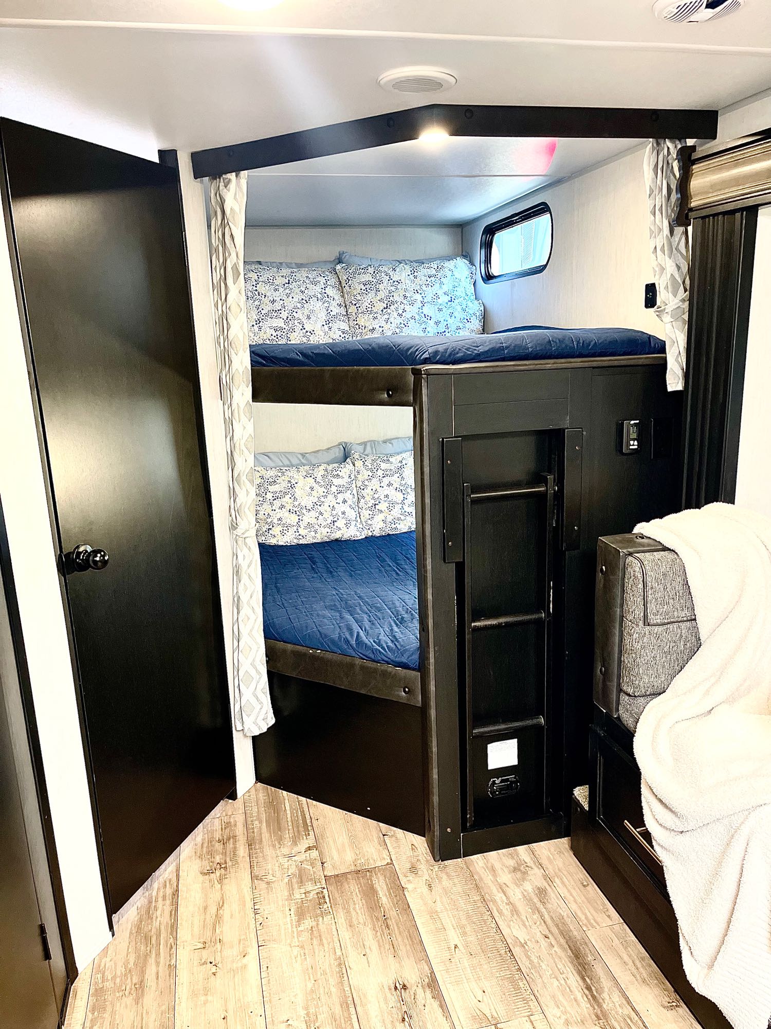 RV rental: Compact bunk beds with blue bedding, a ladder, and adjacent seating area for a cozy interior.. Forest River Cherokee Grey Wolf 2022
