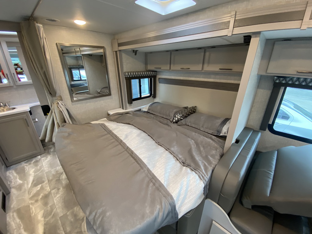 Spacious and modern RV rental bedroom with comfortable bedding, storage, and a small vanity area, perfect for travel.. Thor Motor Coach Echelon LC25 2022