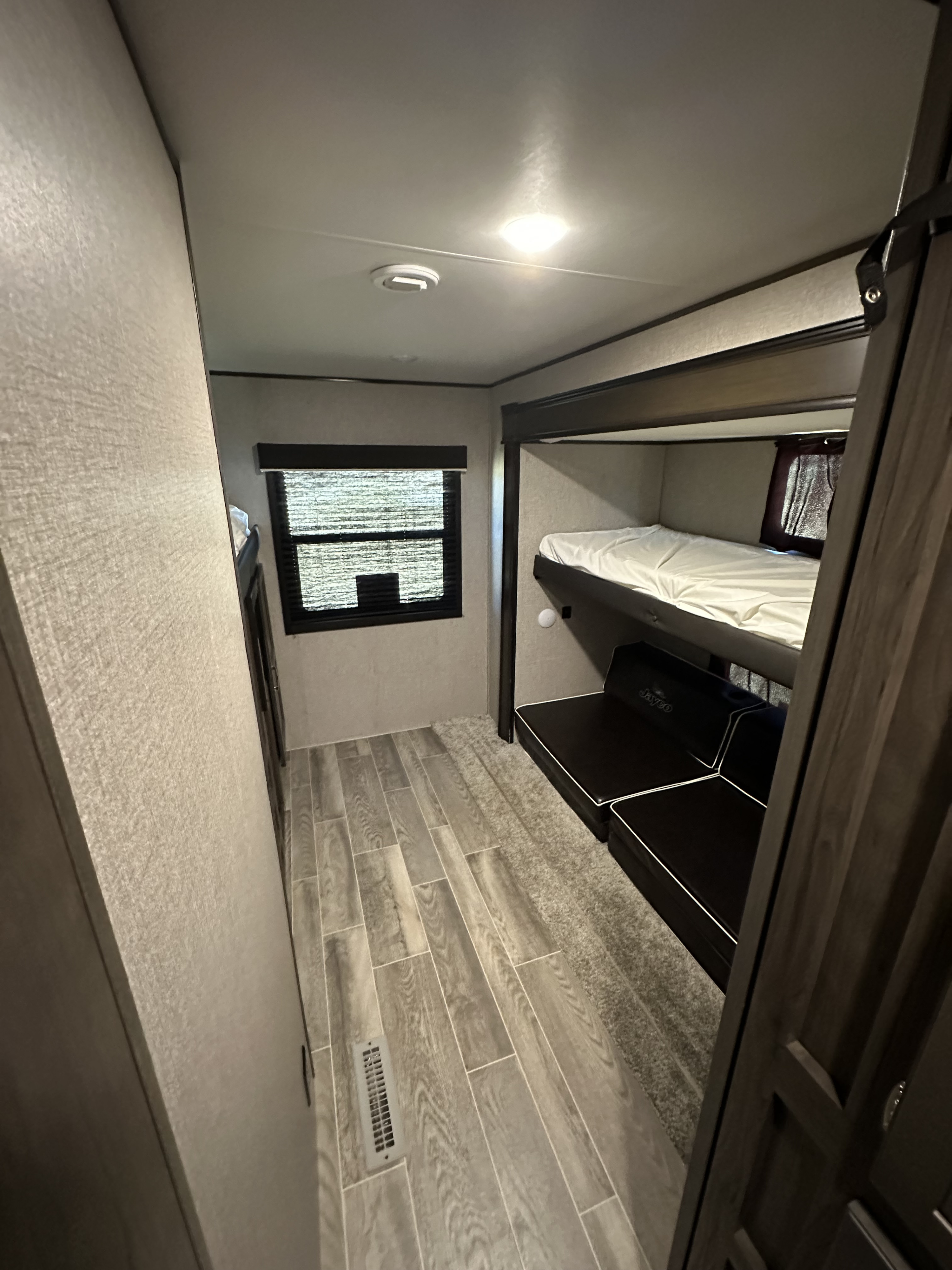 Cozy RV rental interior with bunk beds, lounge seating, window, and mixed flooring.. Jayco Jay Flight 2021