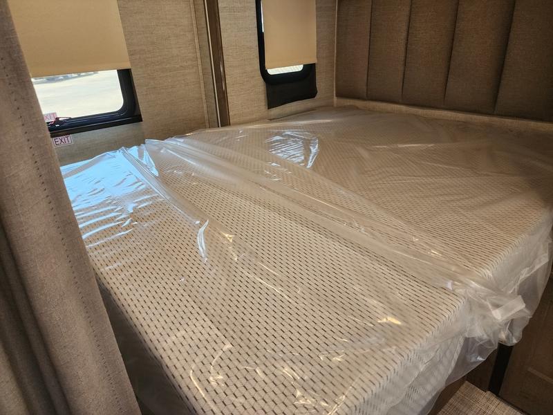 New RV rental bedroom featuring a mattress still in plastic, an 'EXIT' sign, and a window. Ready for your trip!. Entegra Coach Qwest 24L 2024