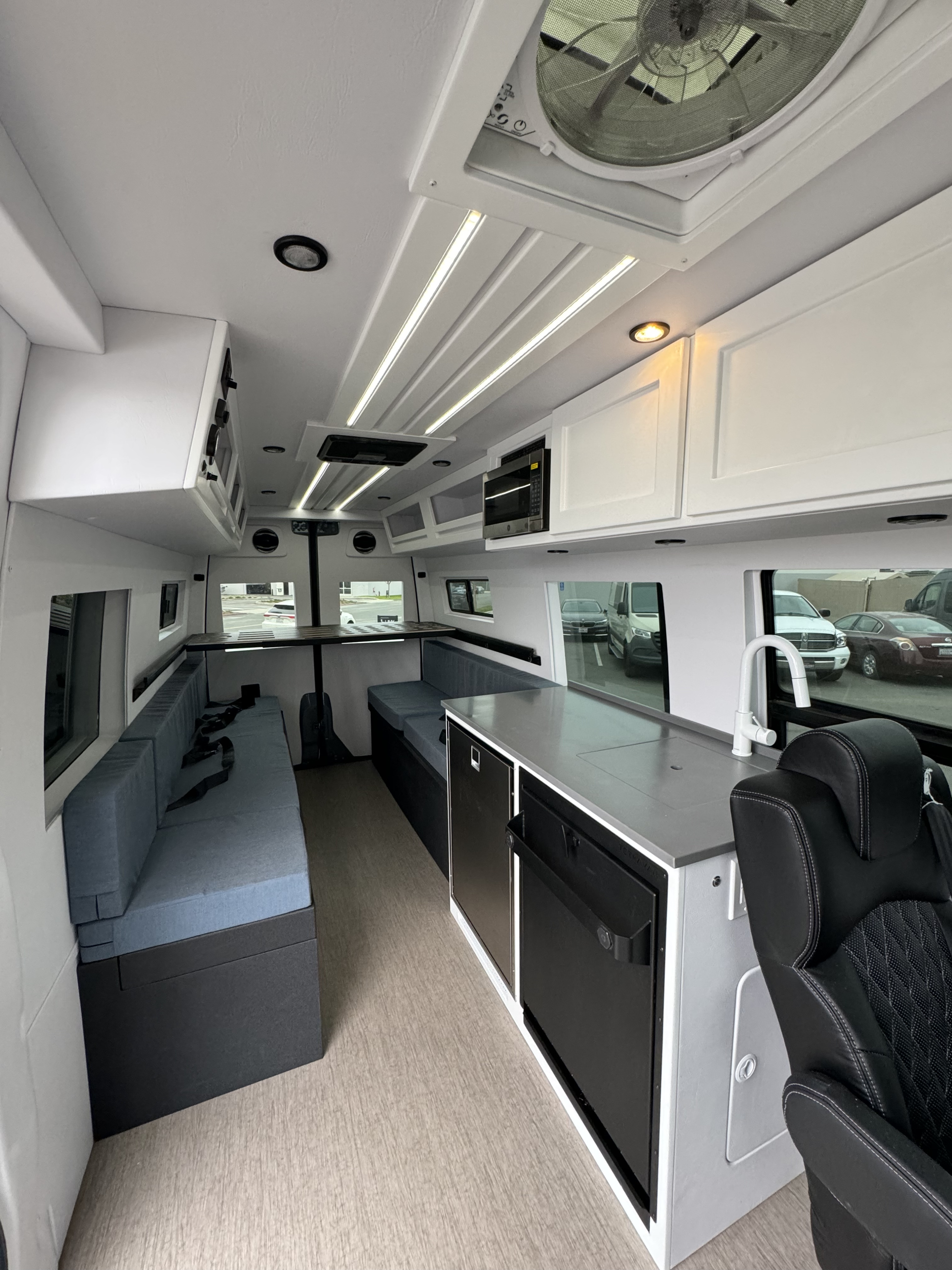 Modern RV rental interior: bright white walls, blue seating, and a fully equipped kitchen with appliances.. Mercedes-Benz Sprinter 2022