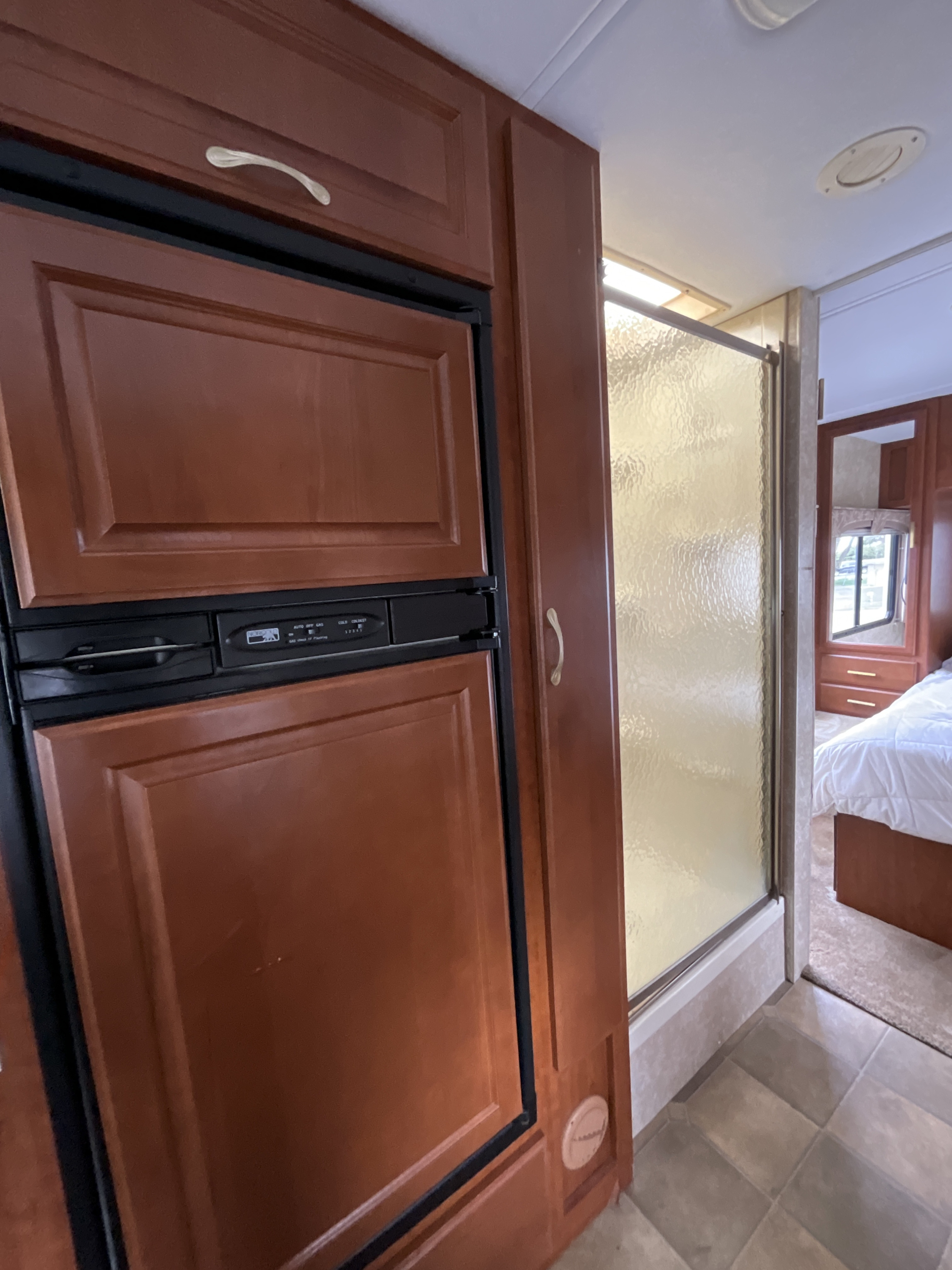 Inside this RV rental, find a wood-paneled refrigerator, compact shower, and comfortable bedroom for your travels.. Thor Motor Coach 31P 2007