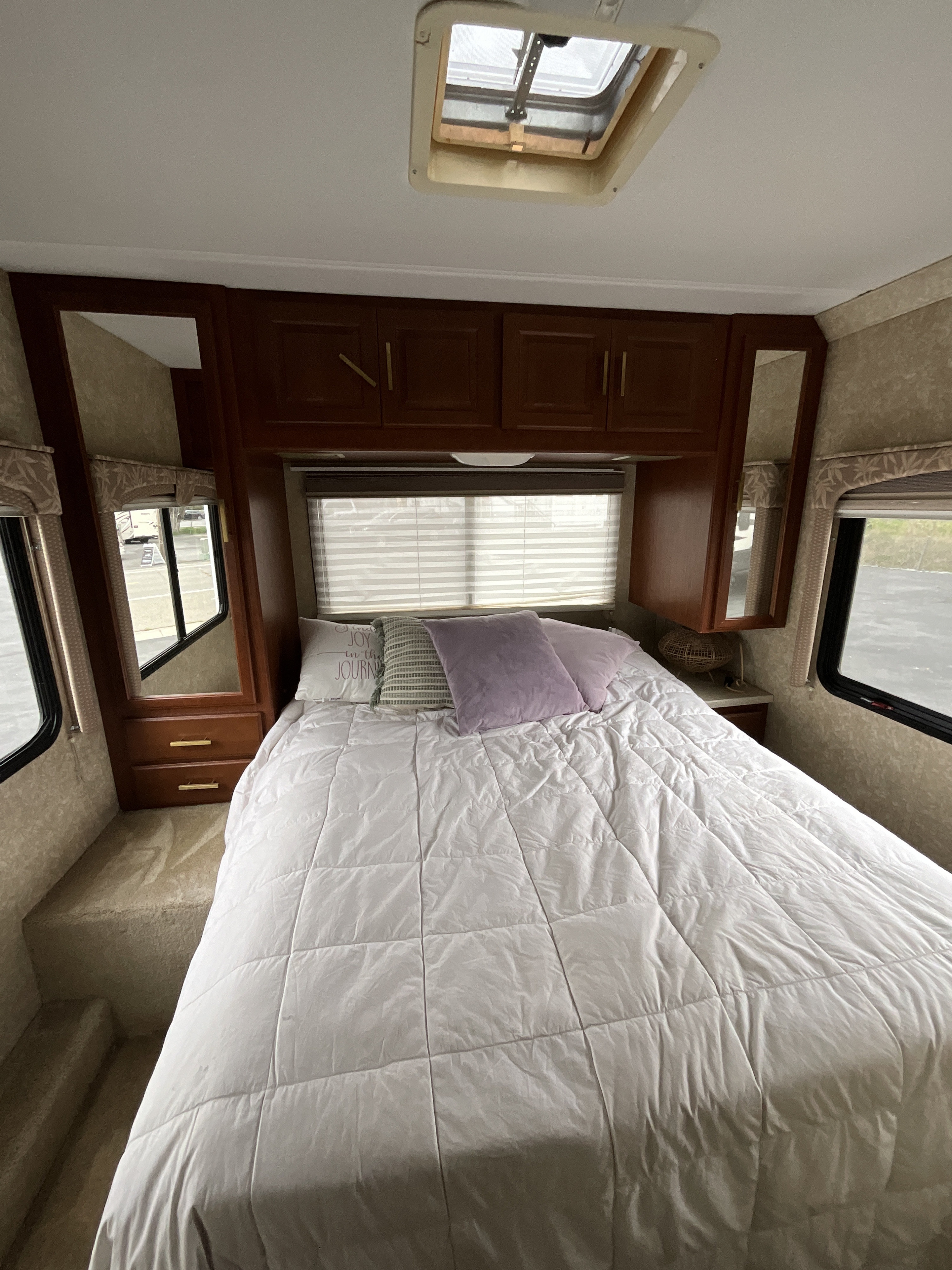 Cozy RV rental bedroom with spacious bed, overhead storage, and natural light from windows and a skylight.. Thor Motor Coach 31P 2007