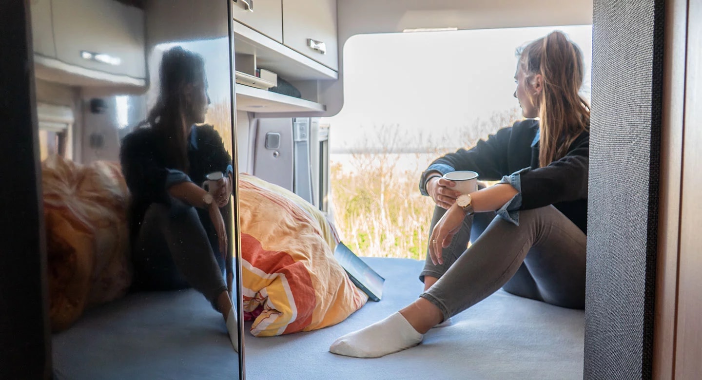 Woman relaxing in an RV rental, enjoying the view from her cozy camper van. Ideal for a serene getaway.. weinsberg caratour 2024