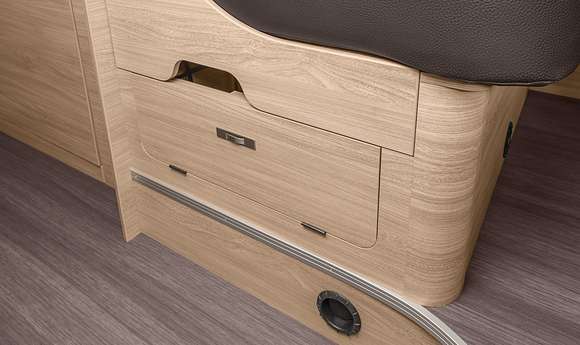 This RV rental features light wood cabinetry, a dark cushioned seat, and a pull-out drawer for efficient storage. Modern interior.. Knaus Boxstar 540mq 2024