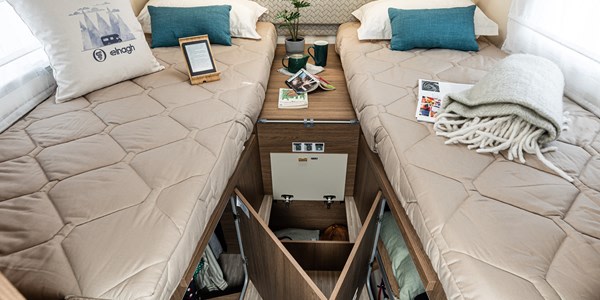 Inside an RV rental, twin beds with integrated under-bed storage flank a central console, offering ample space and convenience.. Elnagh Baron 573 2024