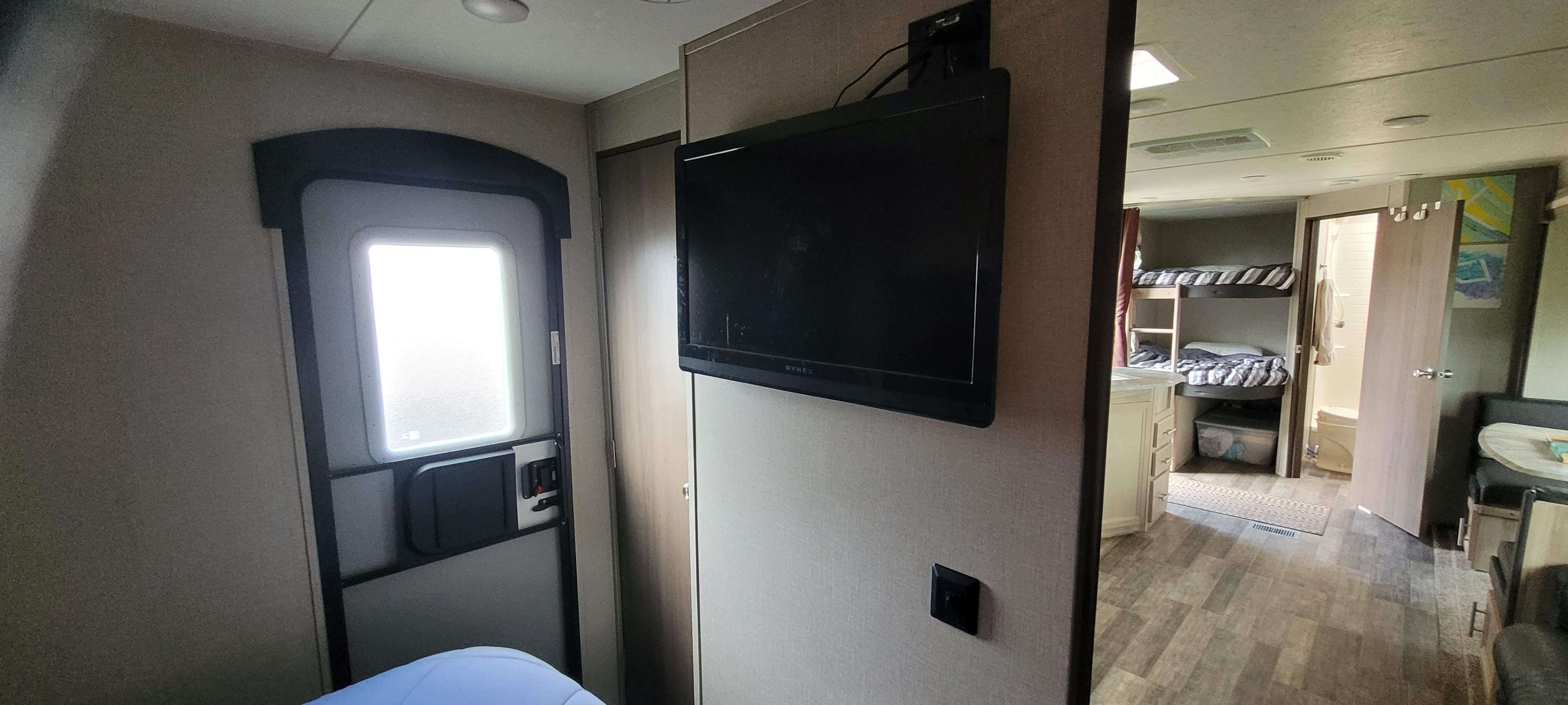 Inside an RV rental: entry door, mounted TV, bunk beds, and a kitchen/dining area are visible, offering a compact living space.. Coachmen Other 2021