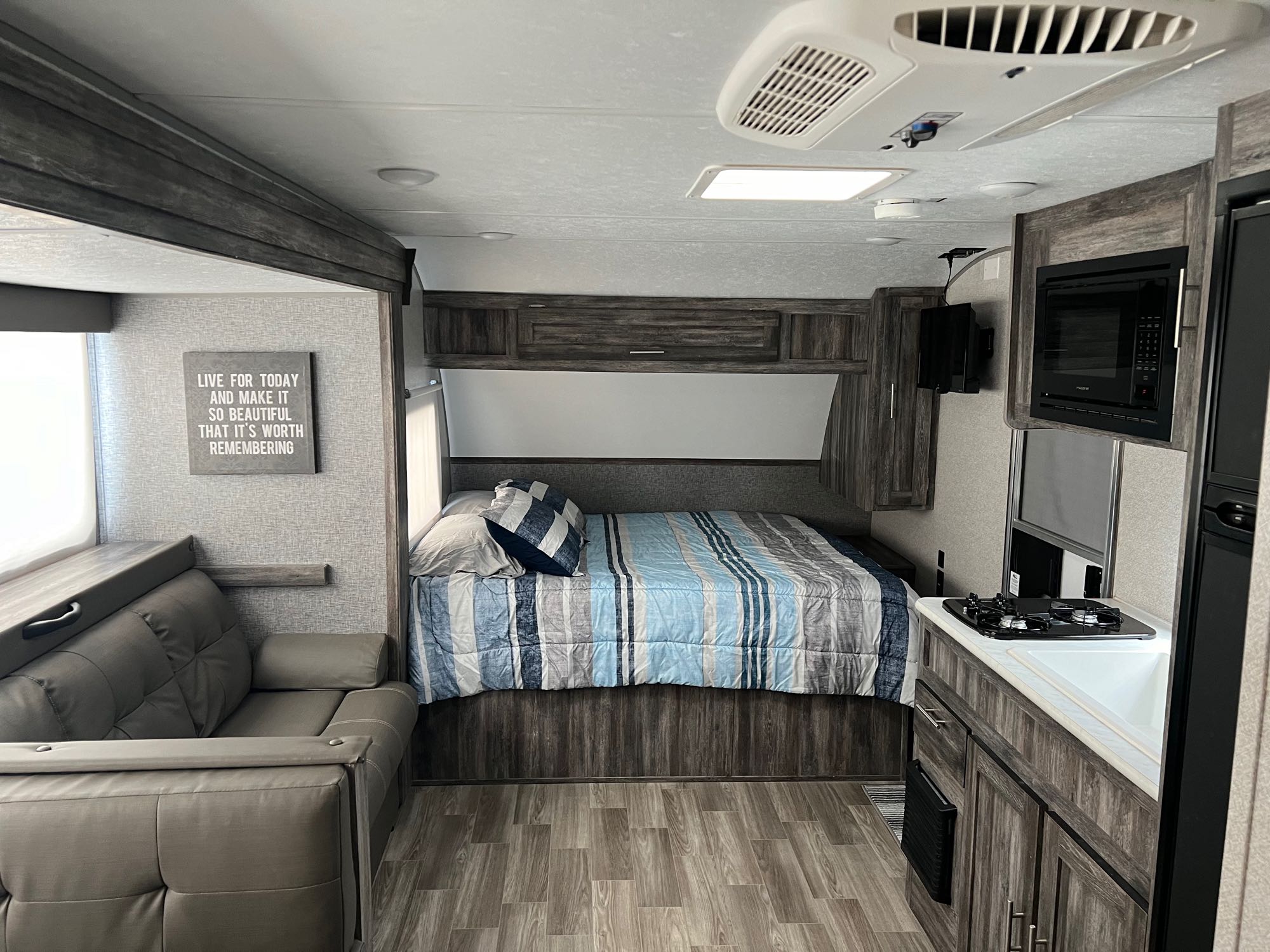 Spacious RV rental interior featuring a cozy bed, sofa, and equipped kitchen, ready for your next adventure.. Forest River Wildwood FSX Platinum 2020
