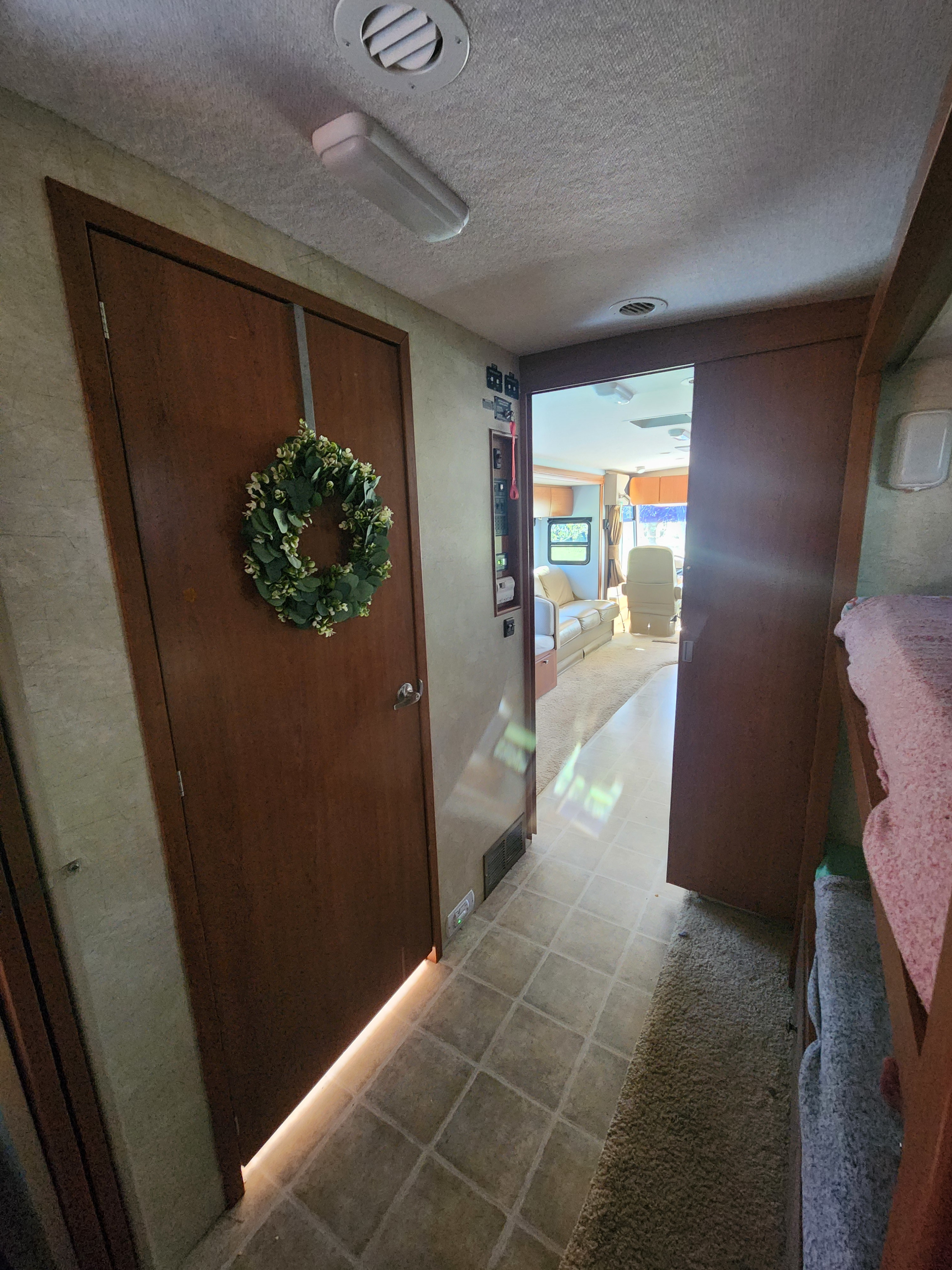 RV rental interior: hall with door & wreath, leading to living area, plus bunk beds in a motorhome.. Itasca Sunova 2008