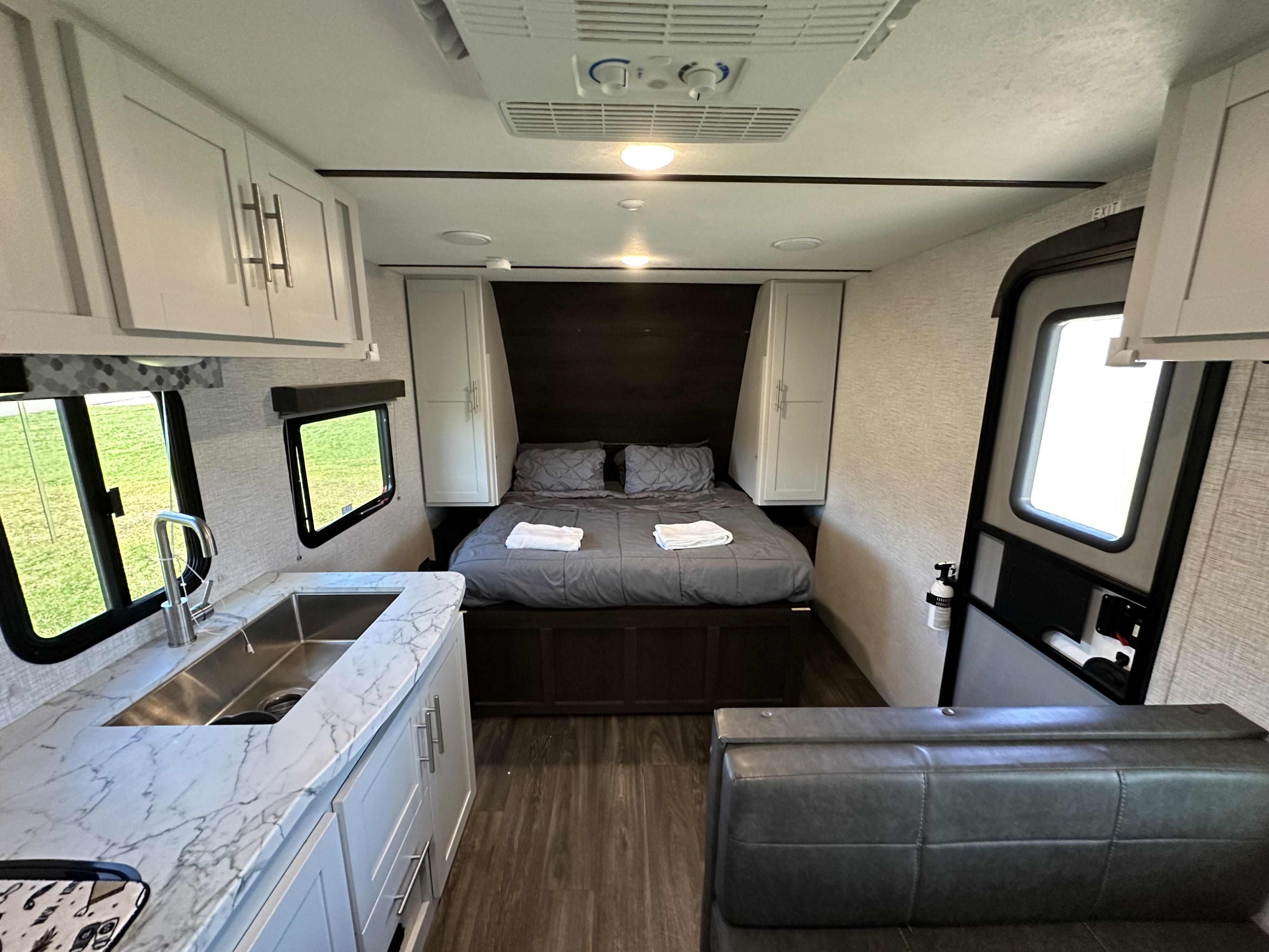 Modern RV rental interior with cozy bed, kitchen area with sink, and seating. Ideal for comfortable travels.. Keystone RV Bullet Crossfire 2021