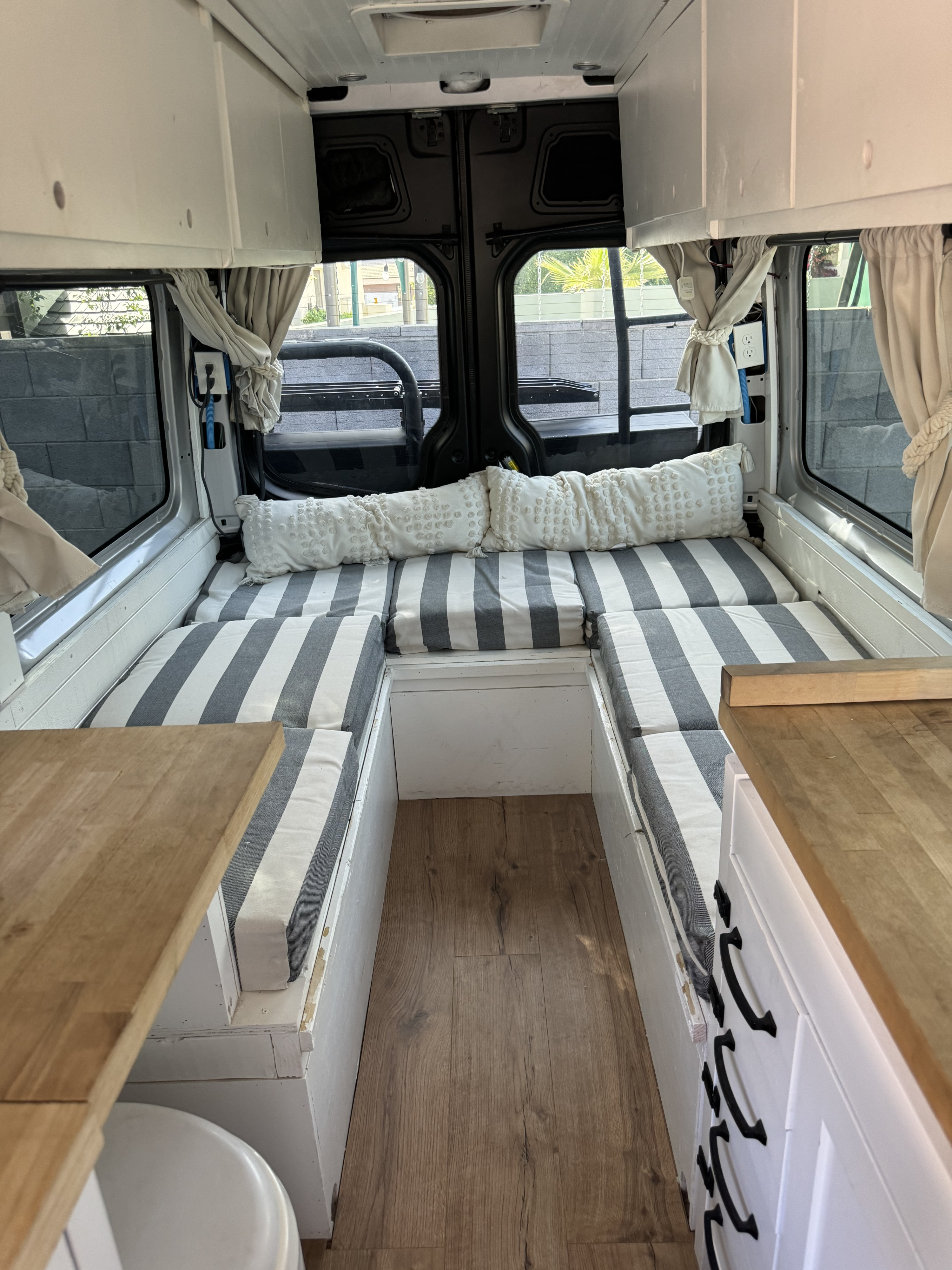 RV rental: View inside a modern camper van with striped sofa, wood floor, overhead cabinets, and built-in storage.. wdzpe8cd0jp648573 2500 2018