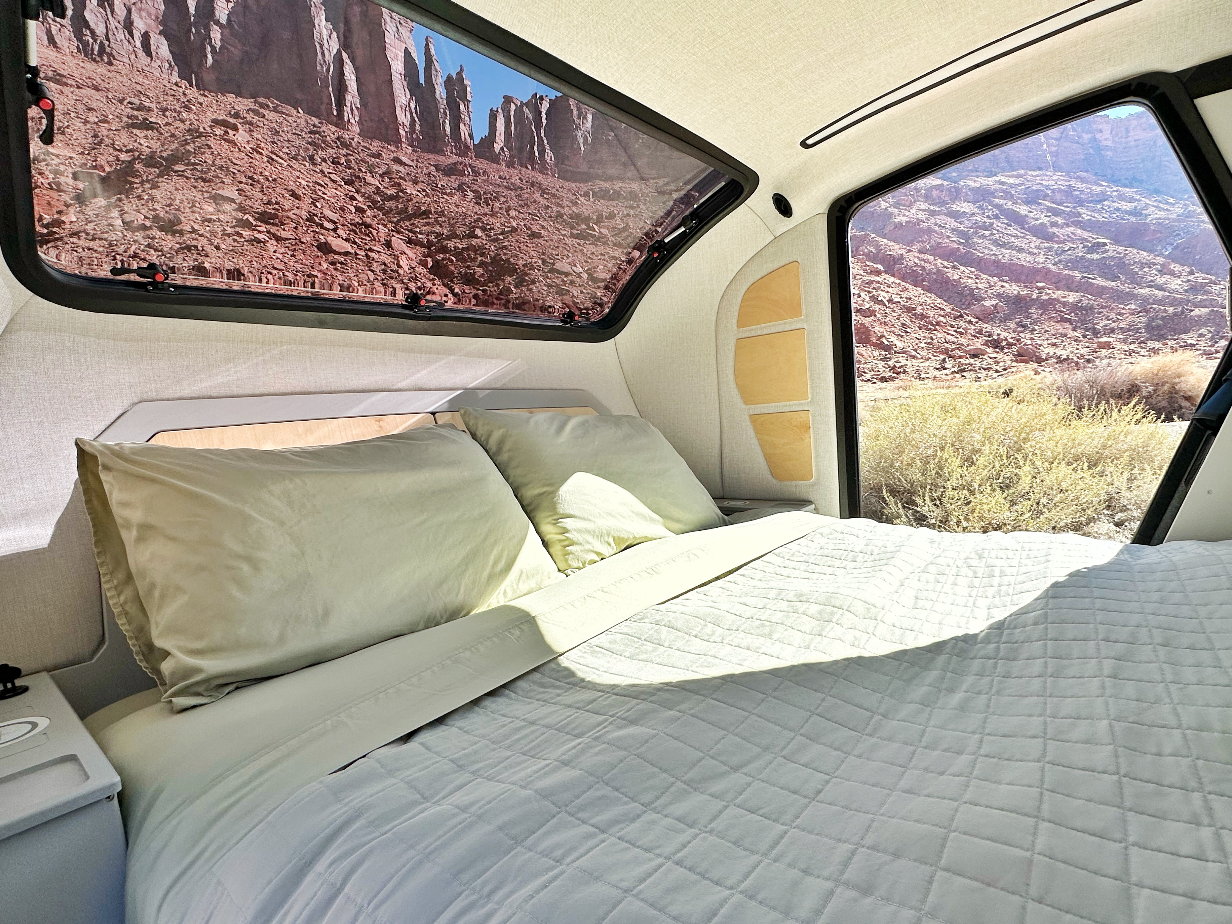 Serene RV rental interior with a comfy bed and large windows revealing dramatic red rock and desert landscapes outside.. Escapod Escapod Trailer 2023