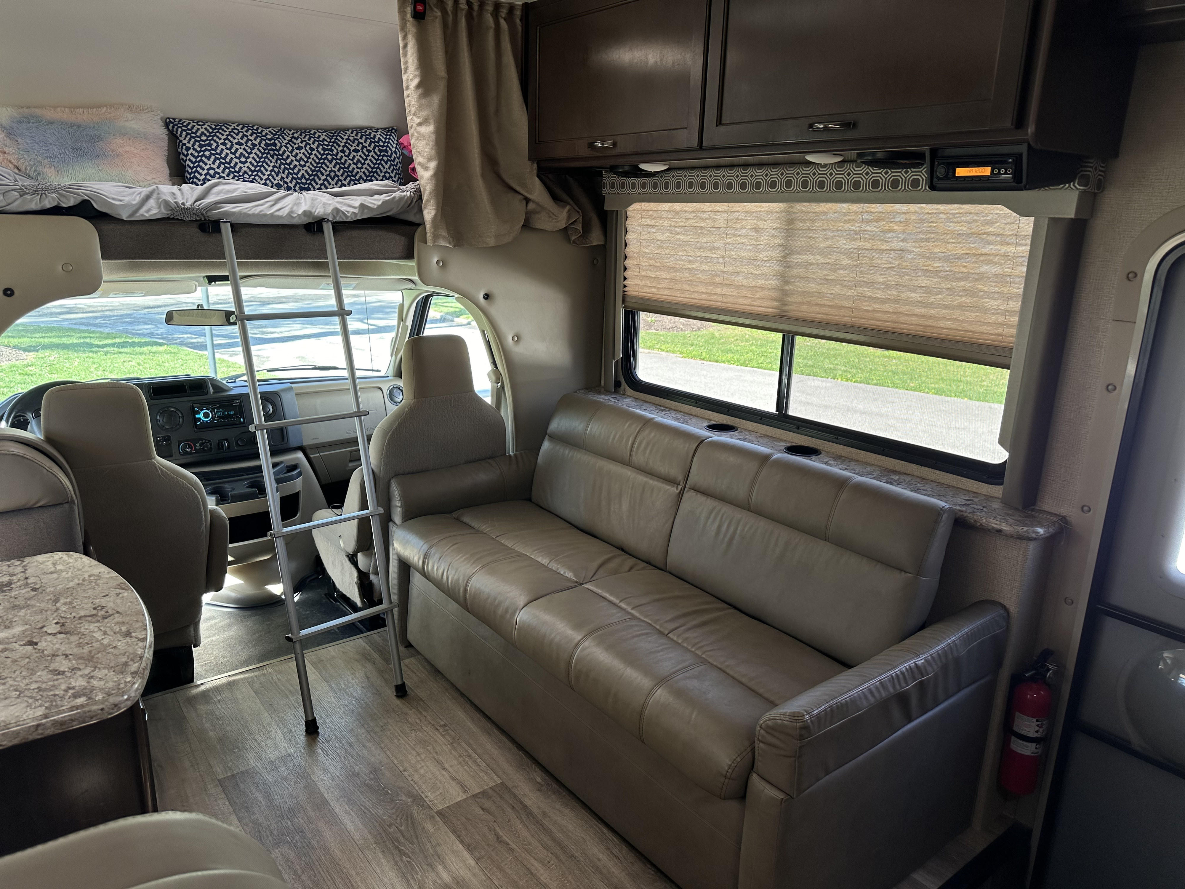 Bright RV rental interior showcasing a bunk bed, comfortable sofa, and front cockpit. Ideal for your next road trip.. Thor Four Winds 2019