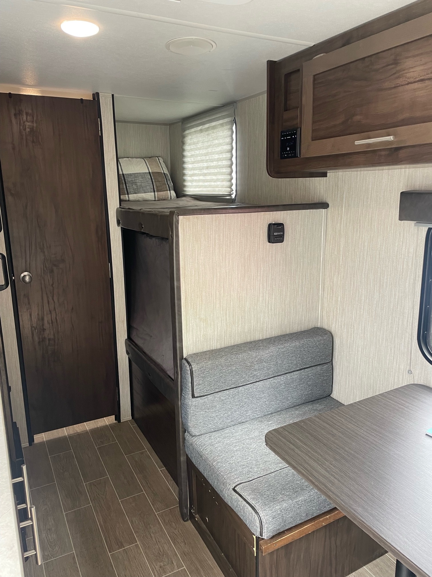 RV rental interior features comfortable bunk beds, a compact dinette with grey cushions, and wood-toned cabinets. Ready for your trip!. Forest River Cherokee Wolf Pup 2020