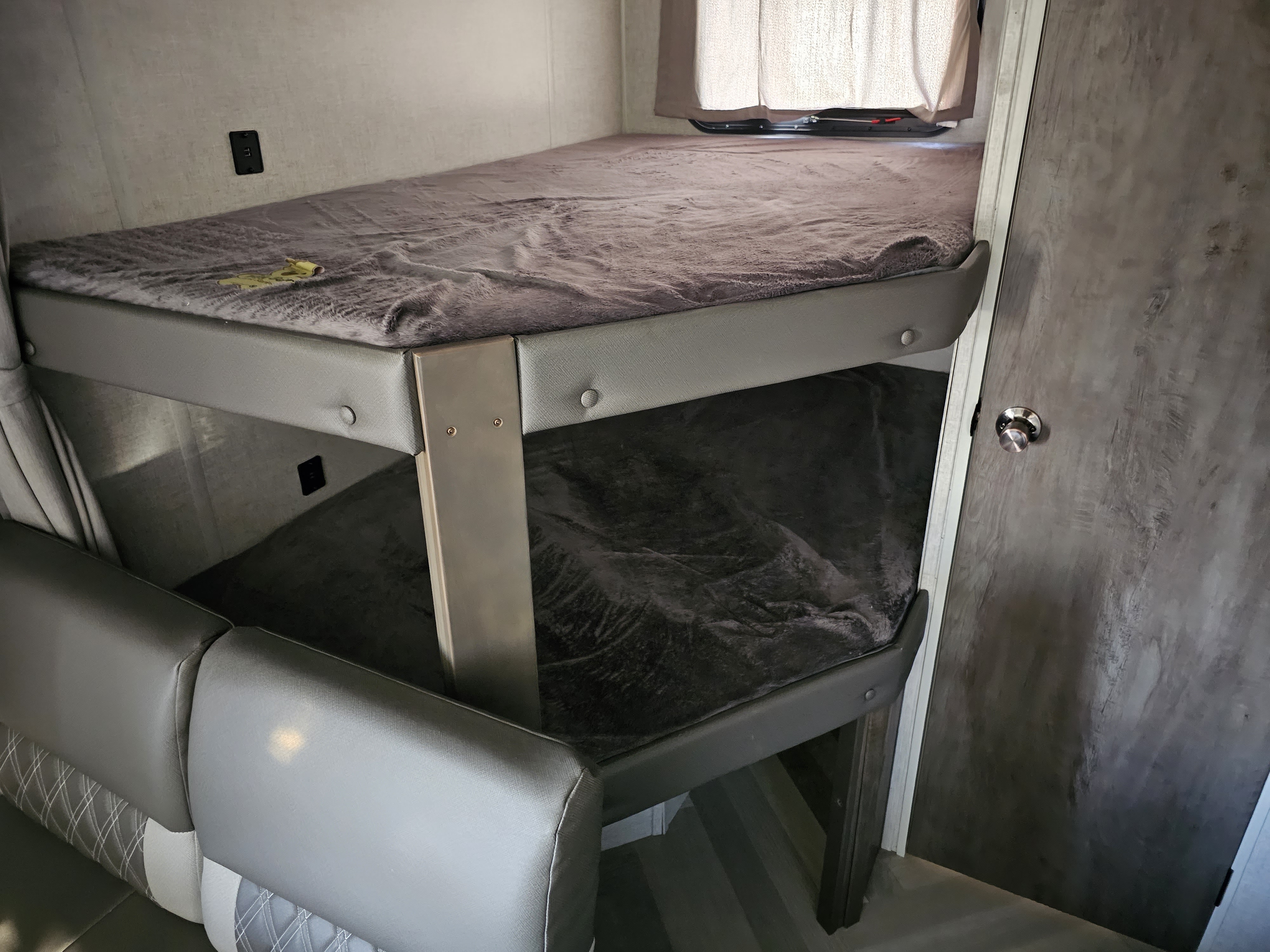 Cozy RV rental bunk beds with soft blankets. Features a sturdy bunk setup, lower seating area, and compact interior.. Forest River Wildwood X-Lite 2021